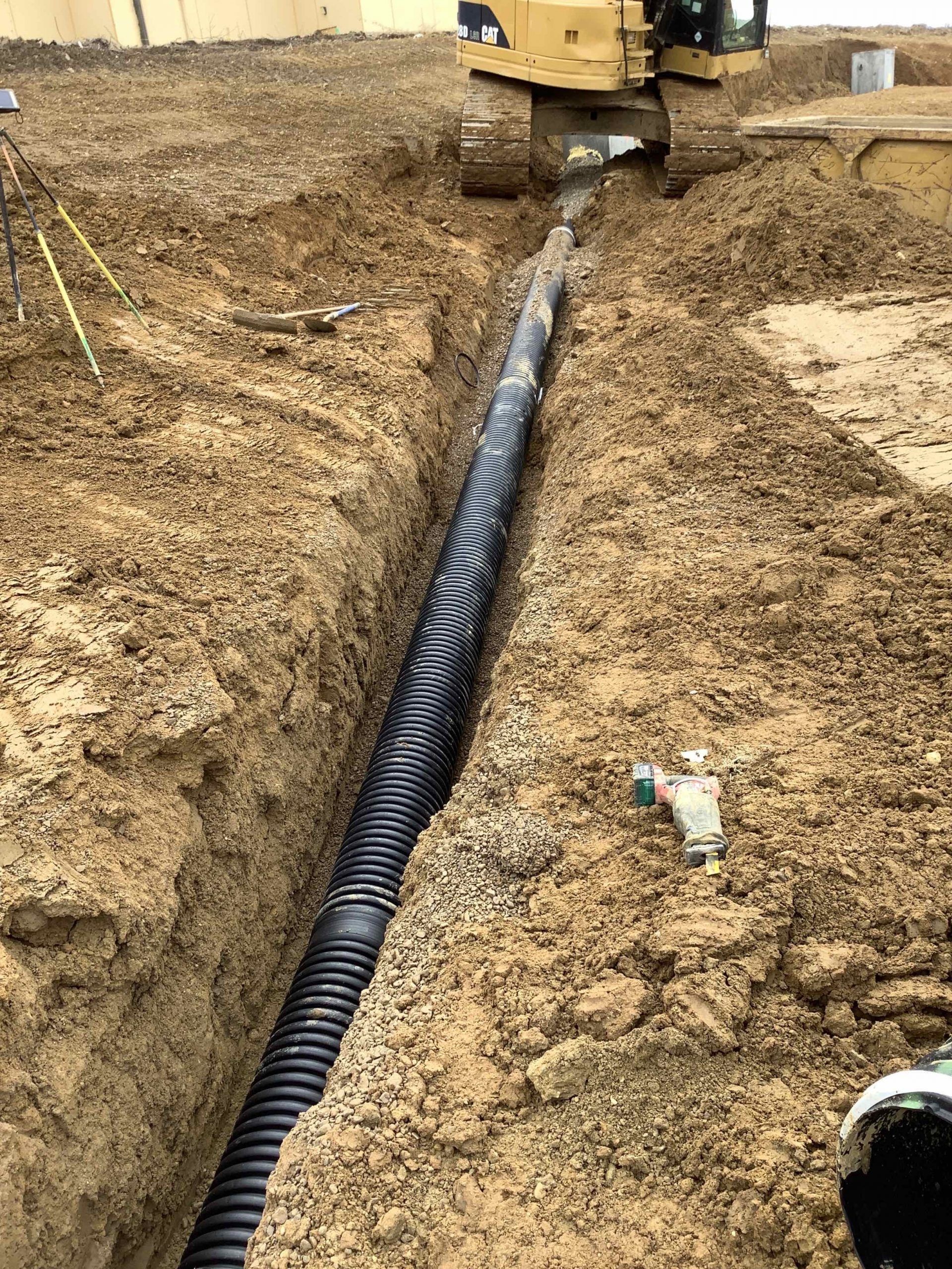 A pipe is being installed in a trench in the dirt.