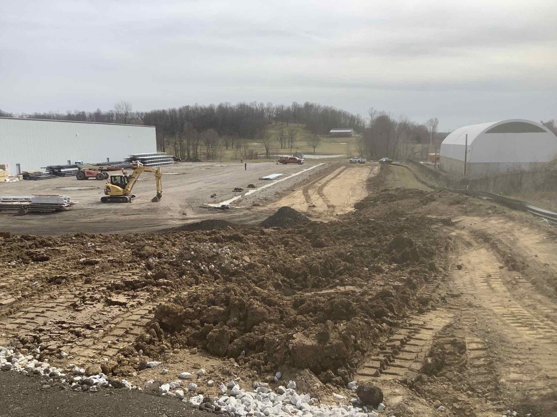 A construction site with a lot of dirt and a building in the background.