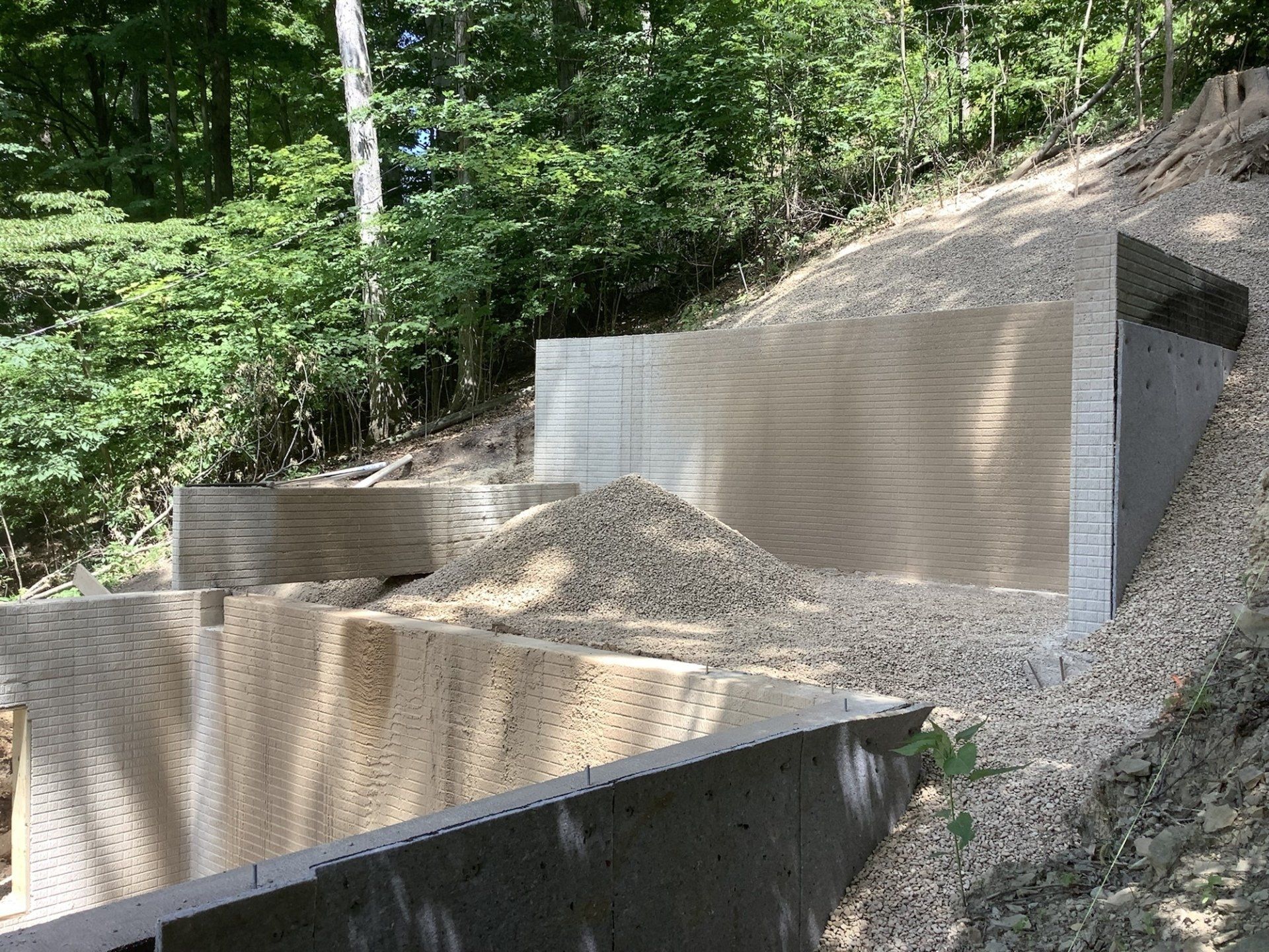 A pile of gravel is sitting on top of a hill next to a concrete wall.