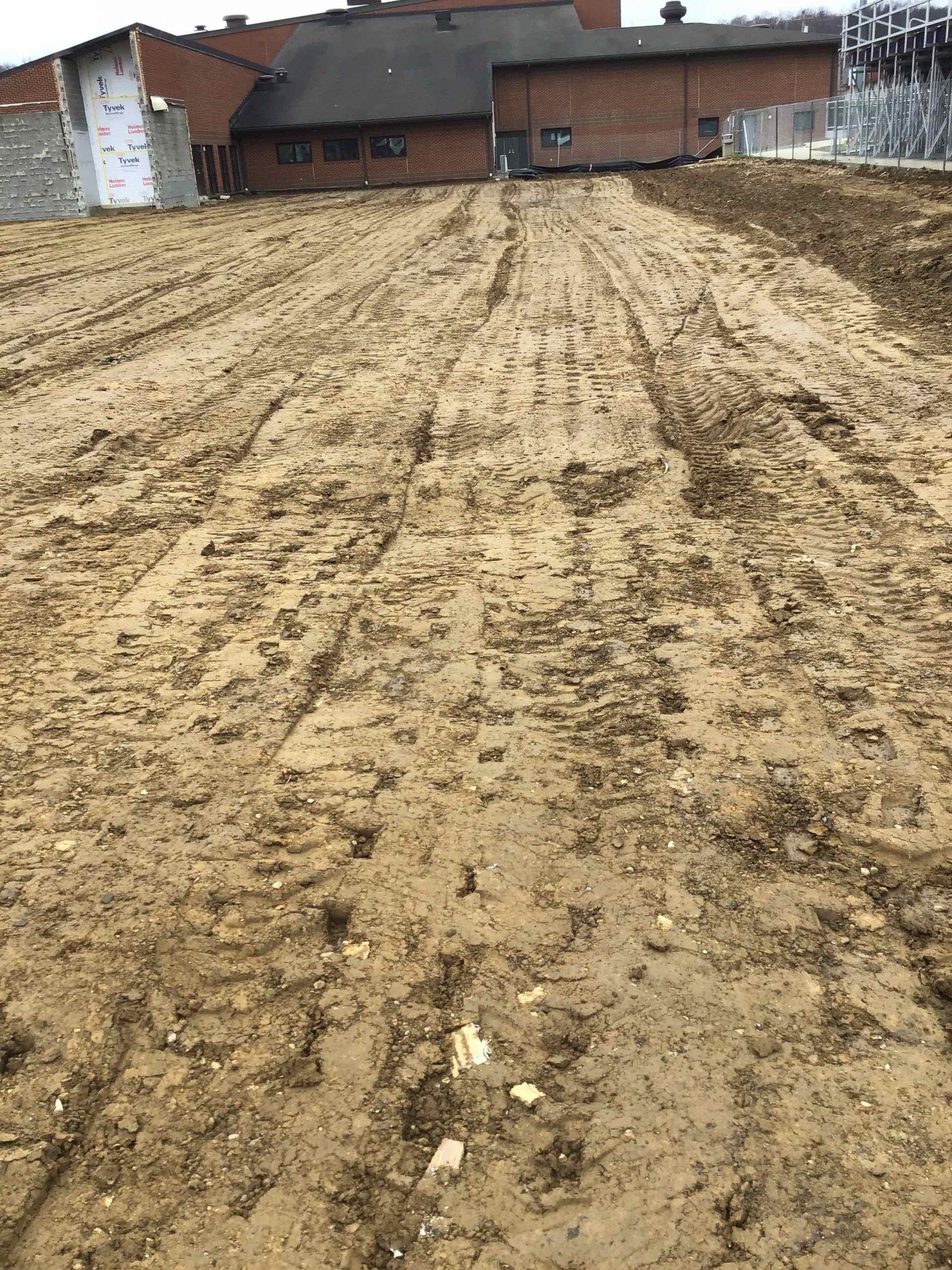 A dirt field with a brick building in the background.