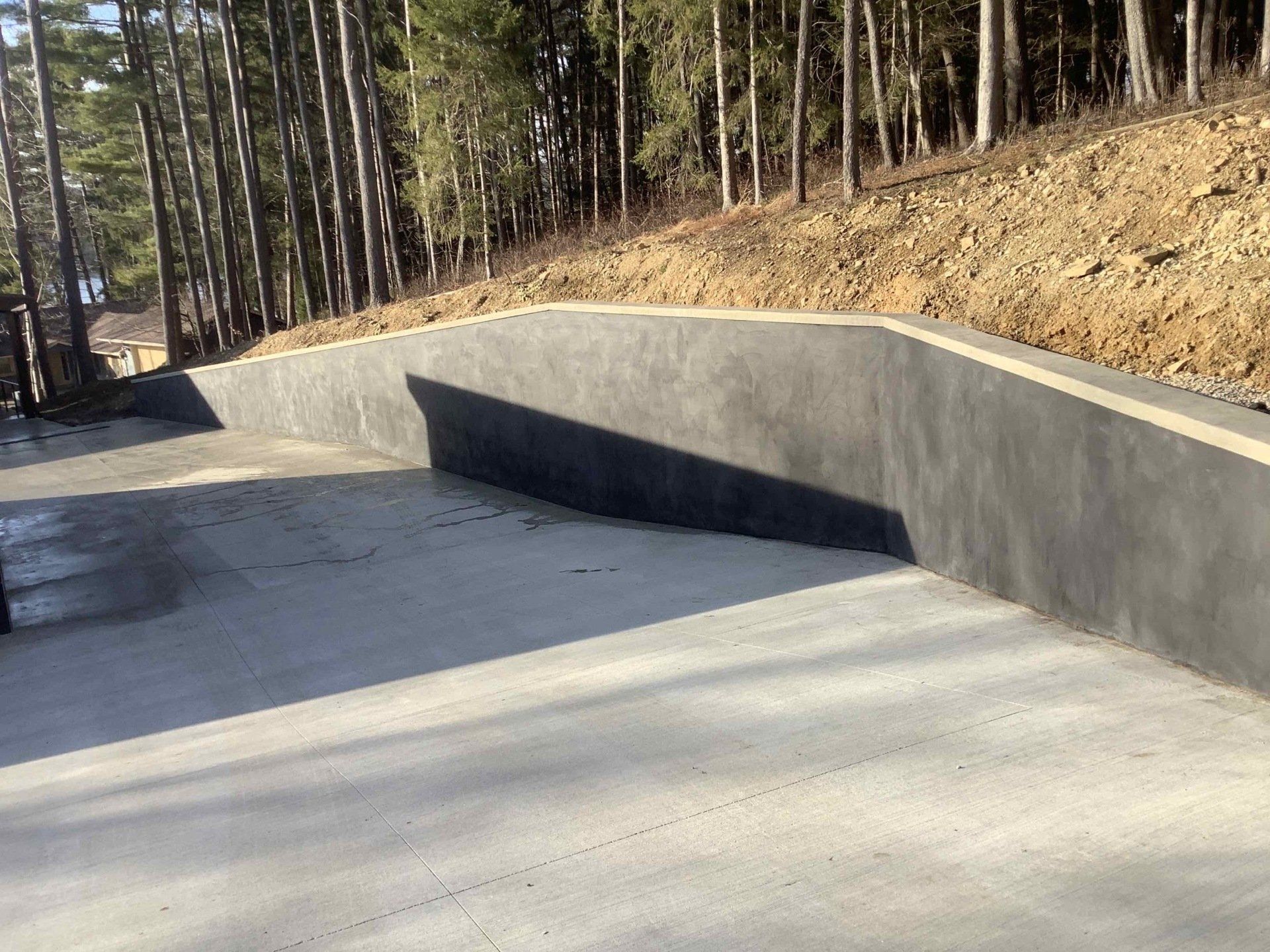 A concrete wall is surrounded by trees on a hillside