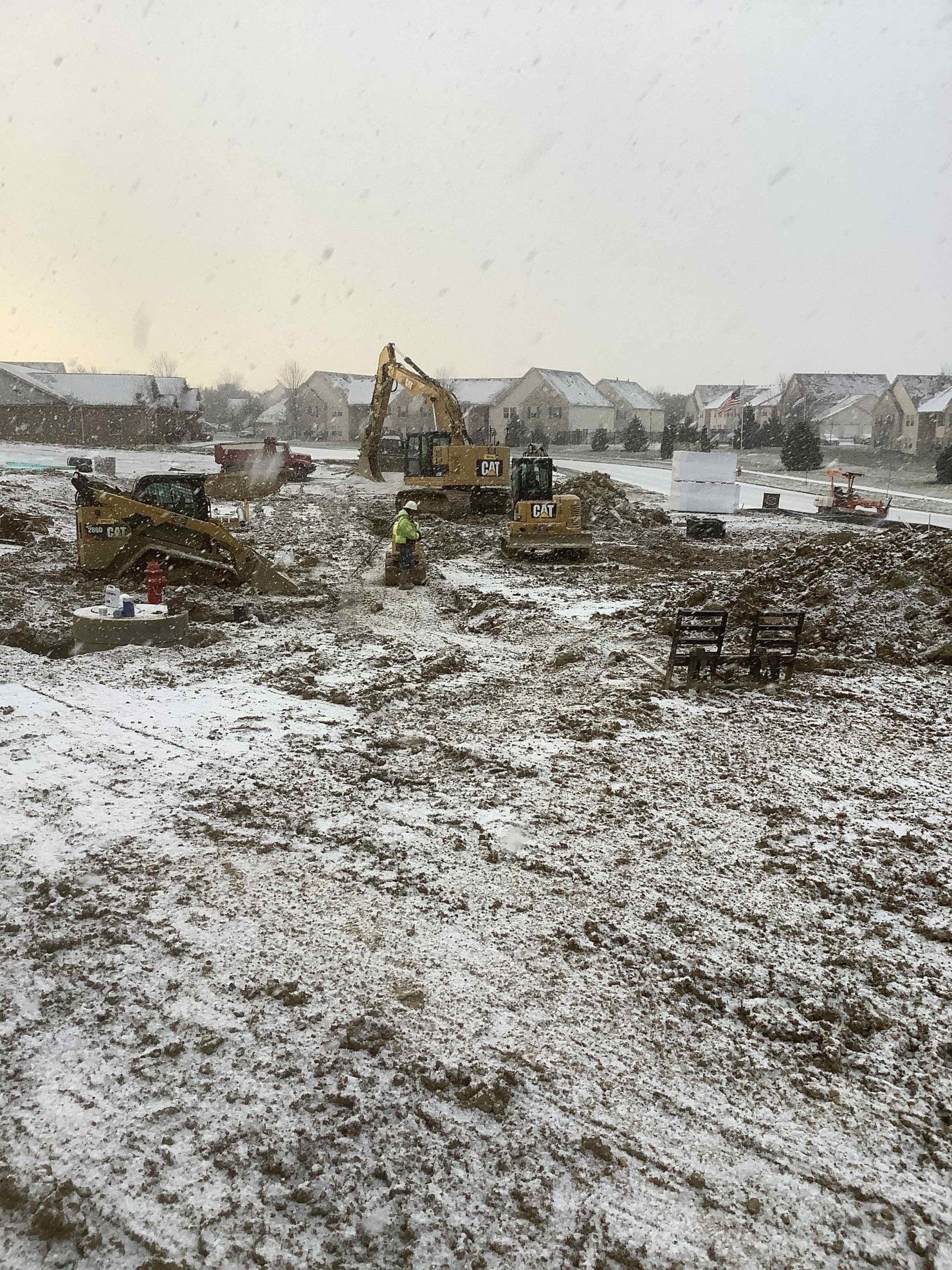 A group of construction vehicles are working on a snowy field.
