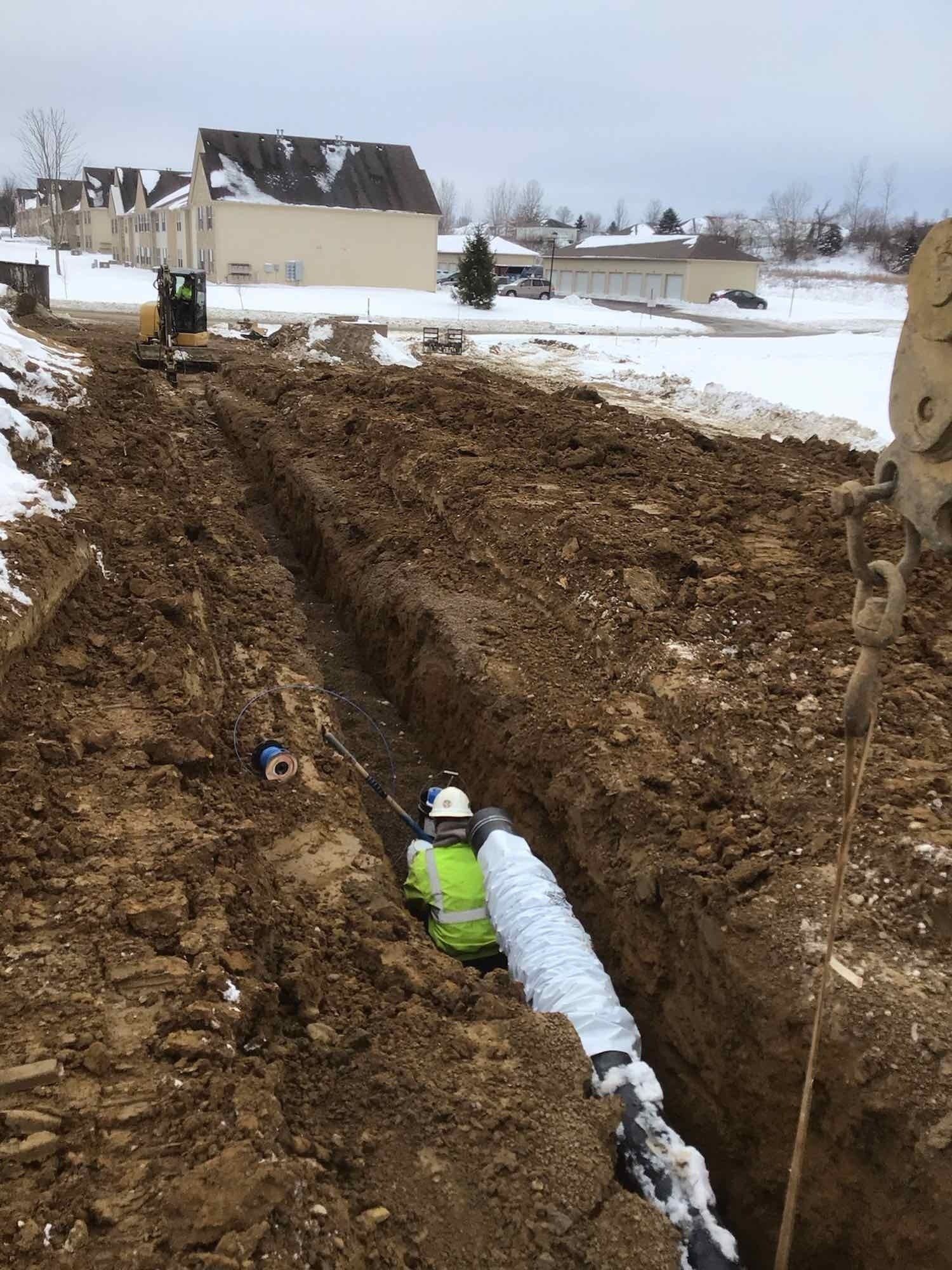 A man is laying a pipe in the dirt.