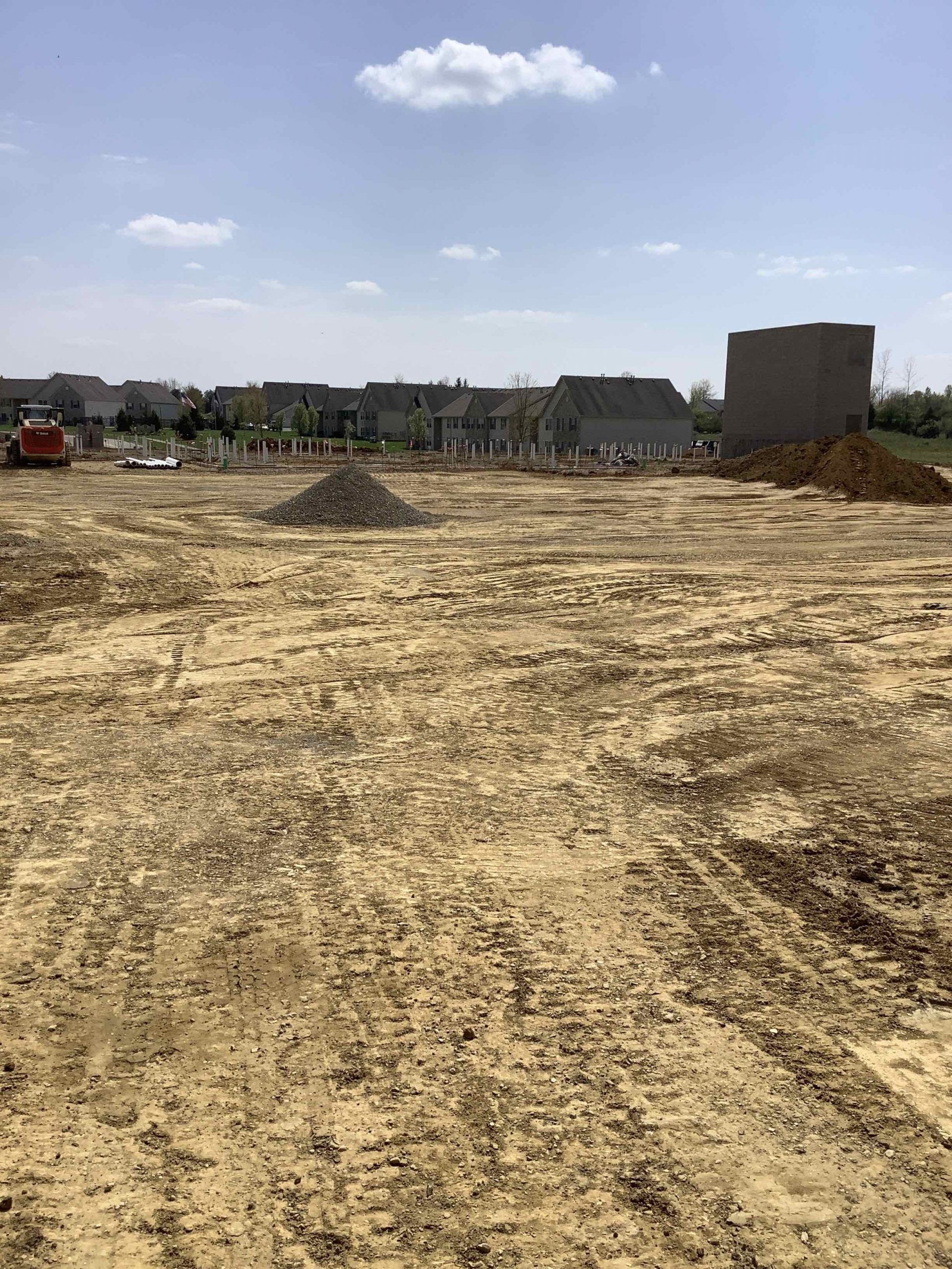 A large dirt field with a house in the background.