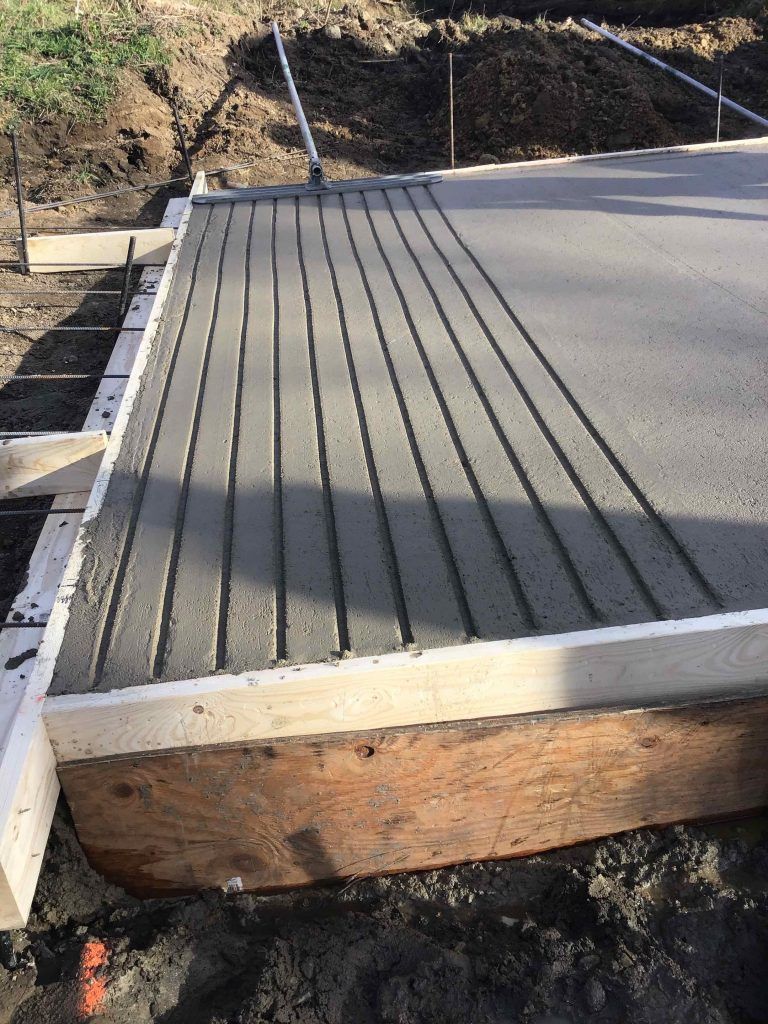 A concrete driveway is being built in the dirt.