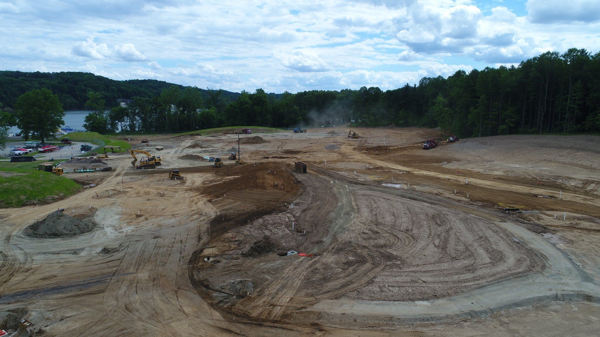 An aerial view of a construction site with a lot of dirt and trees in the background.