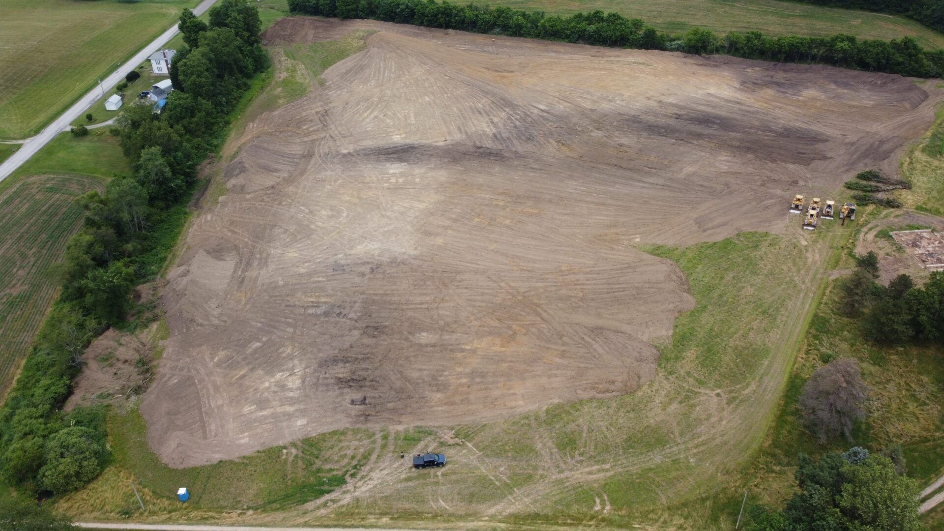 An aerial view of a large dirt field surrounded by trees.