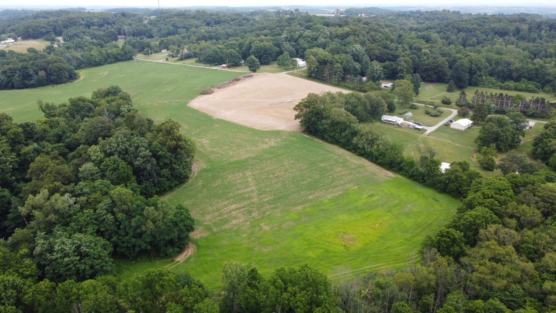 An aerial view of a large grassy field surrounded by trees.