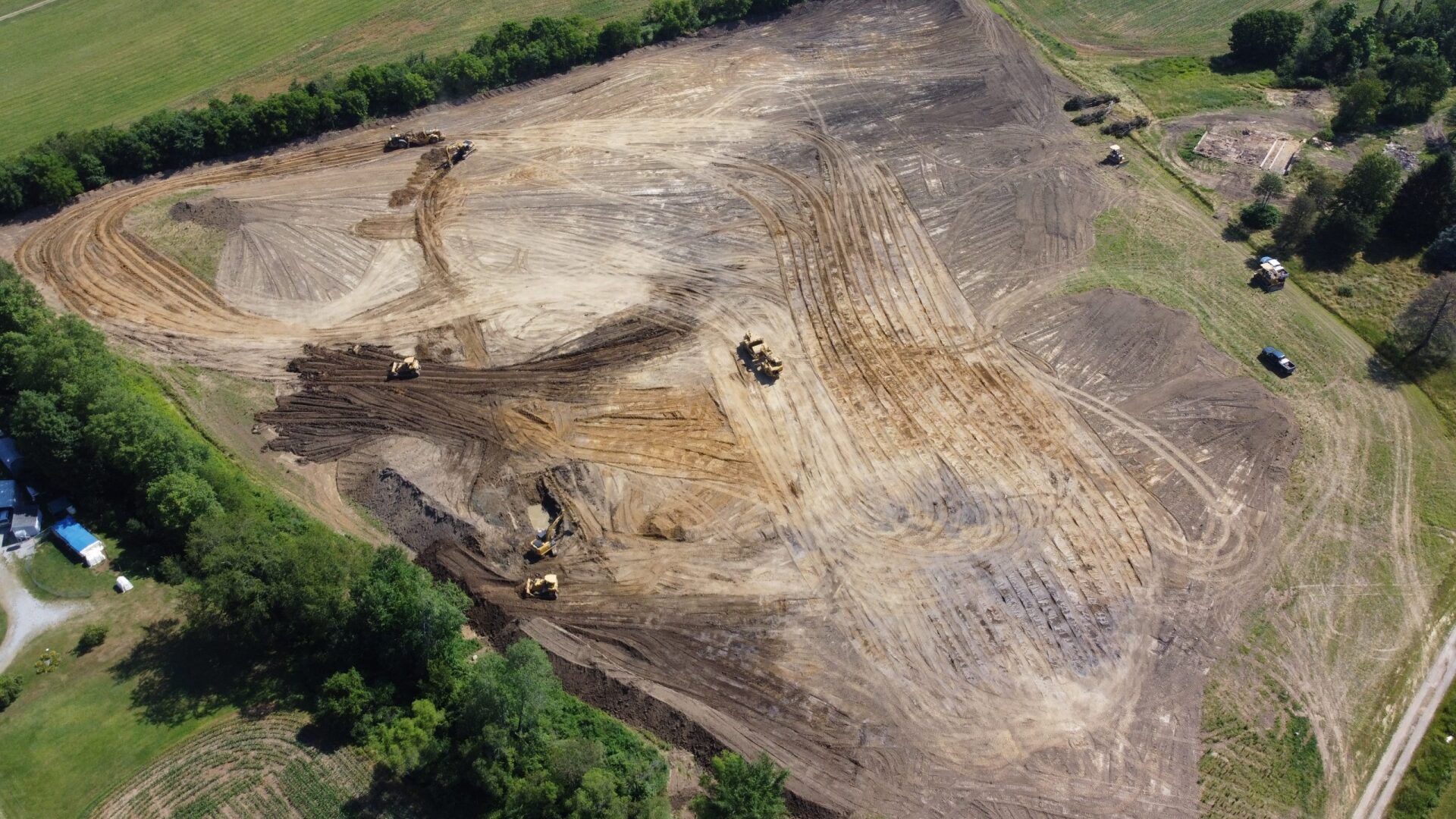 An aerial view of a large dirt field surrounded by trees.