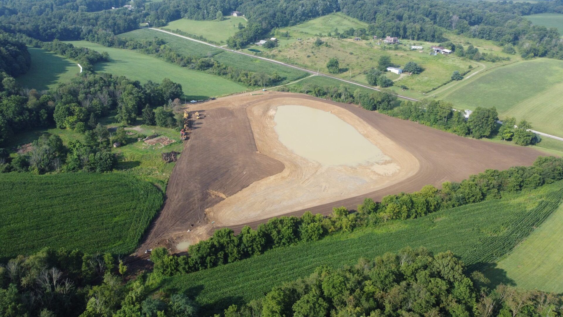 An aerial view of a large field surrounded by trees and fields.