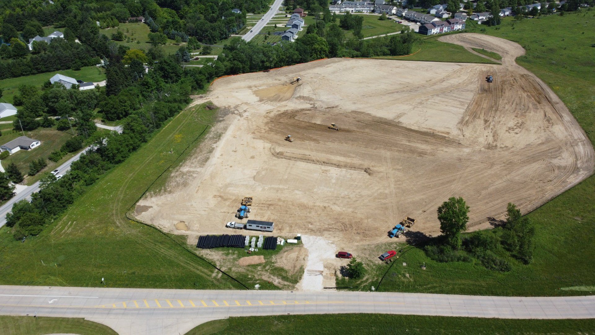 An aerial view of a large dirt field next to a road.