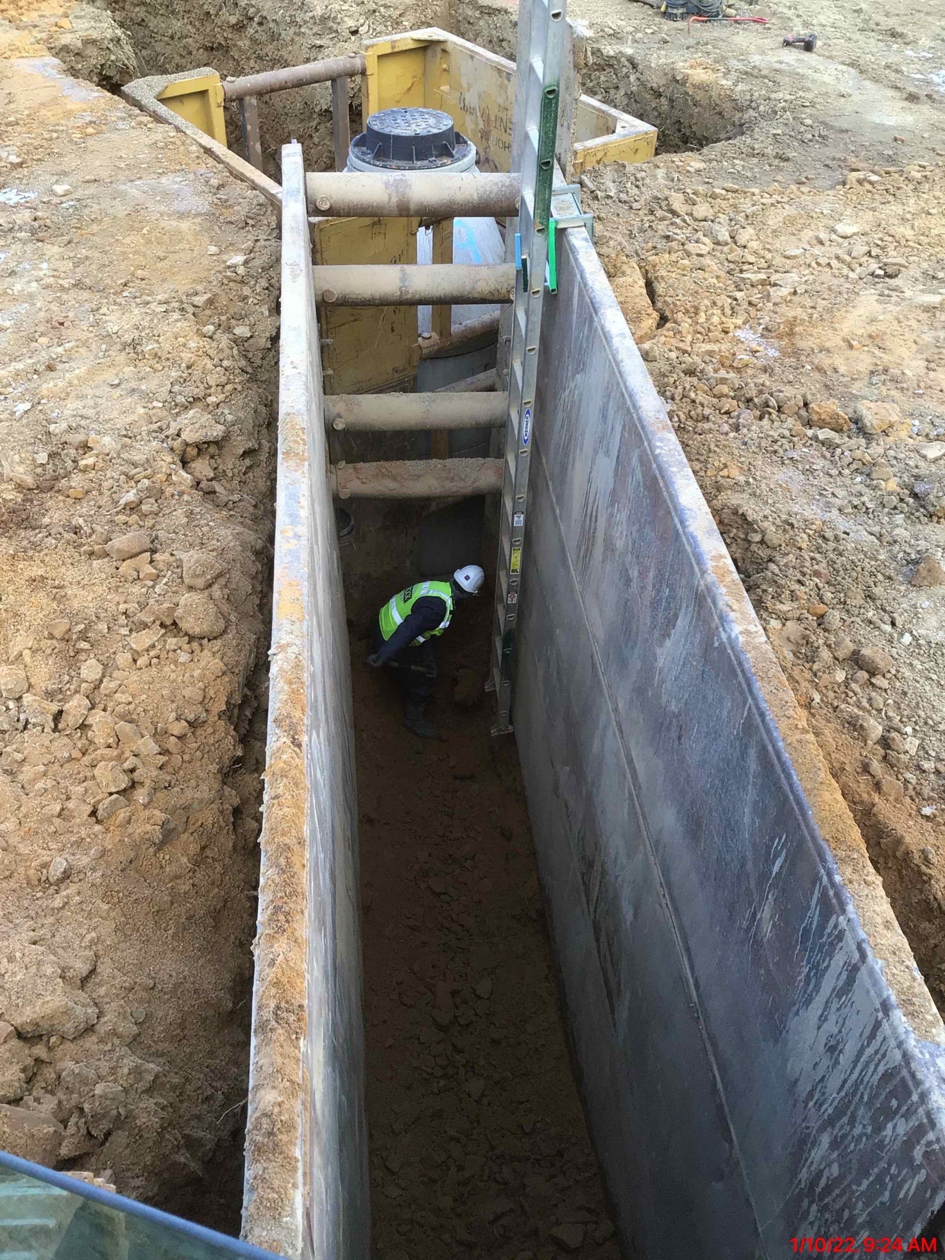 A man is working in a trench with a ladder.