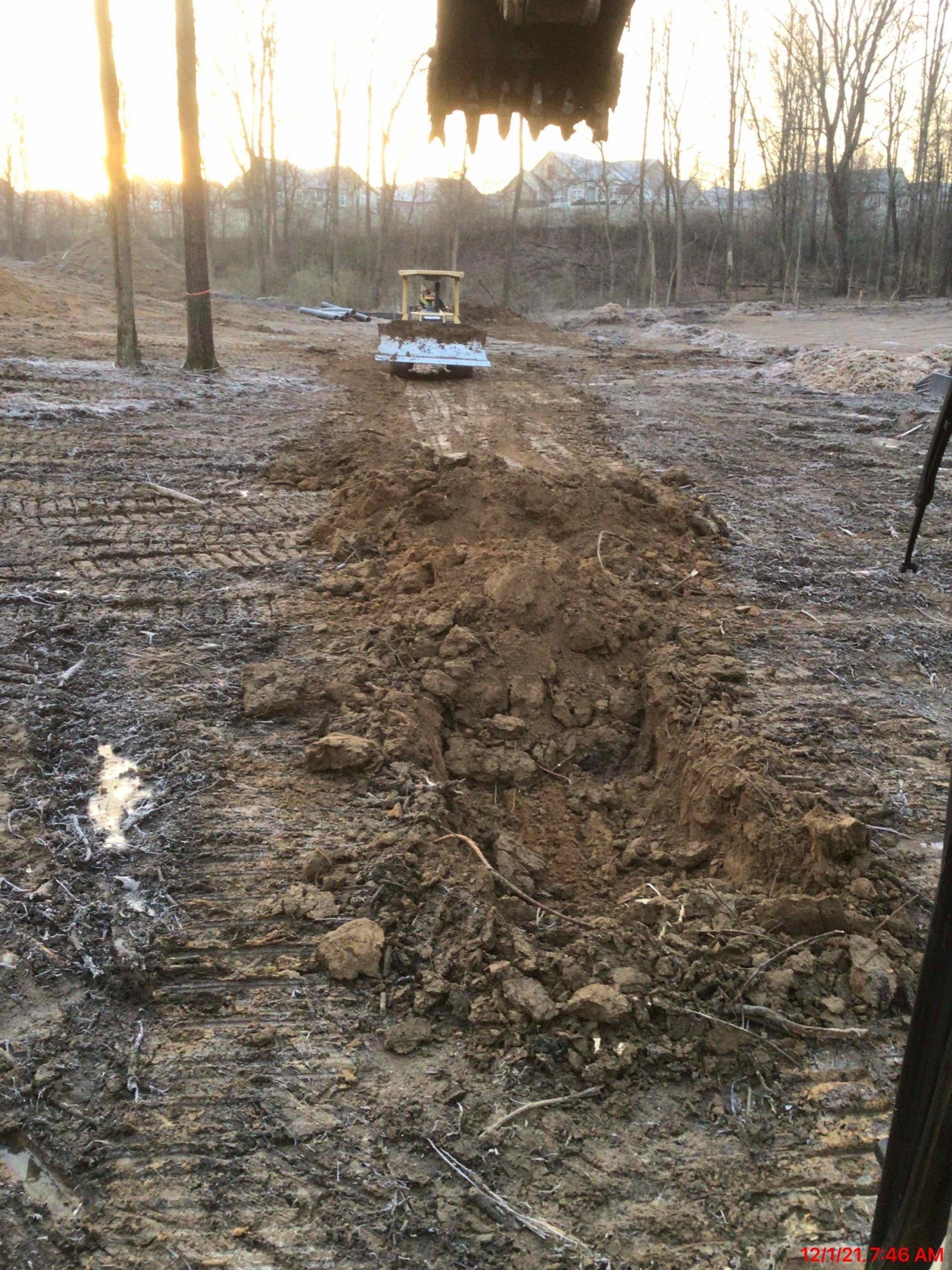 A bulldozer is driving down a dirt road in the woods.
