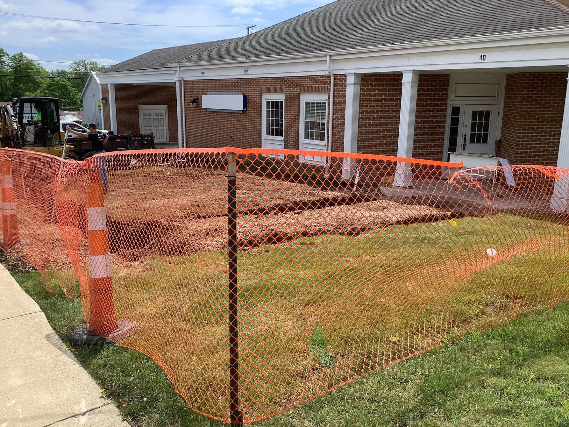 The front yard of the building is surrounded by an orange fence.