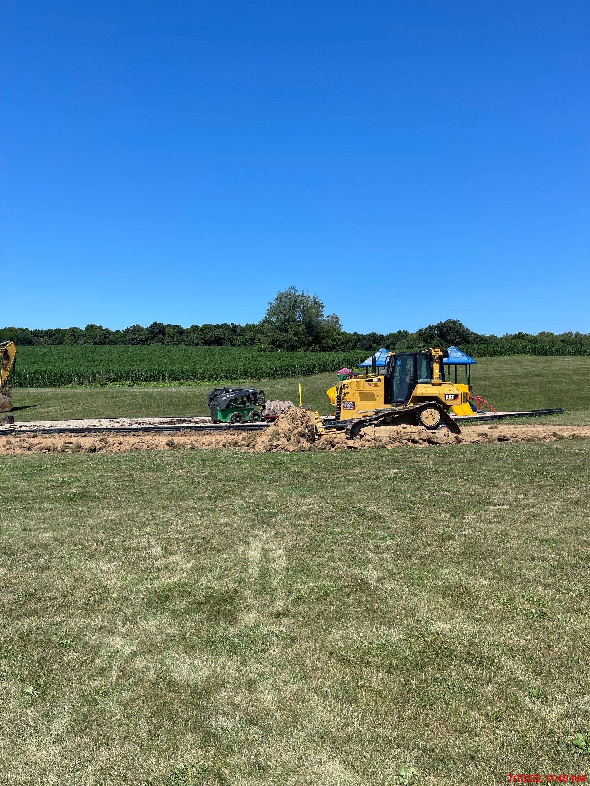 A bulldozer is digging a hole in a grassy field.