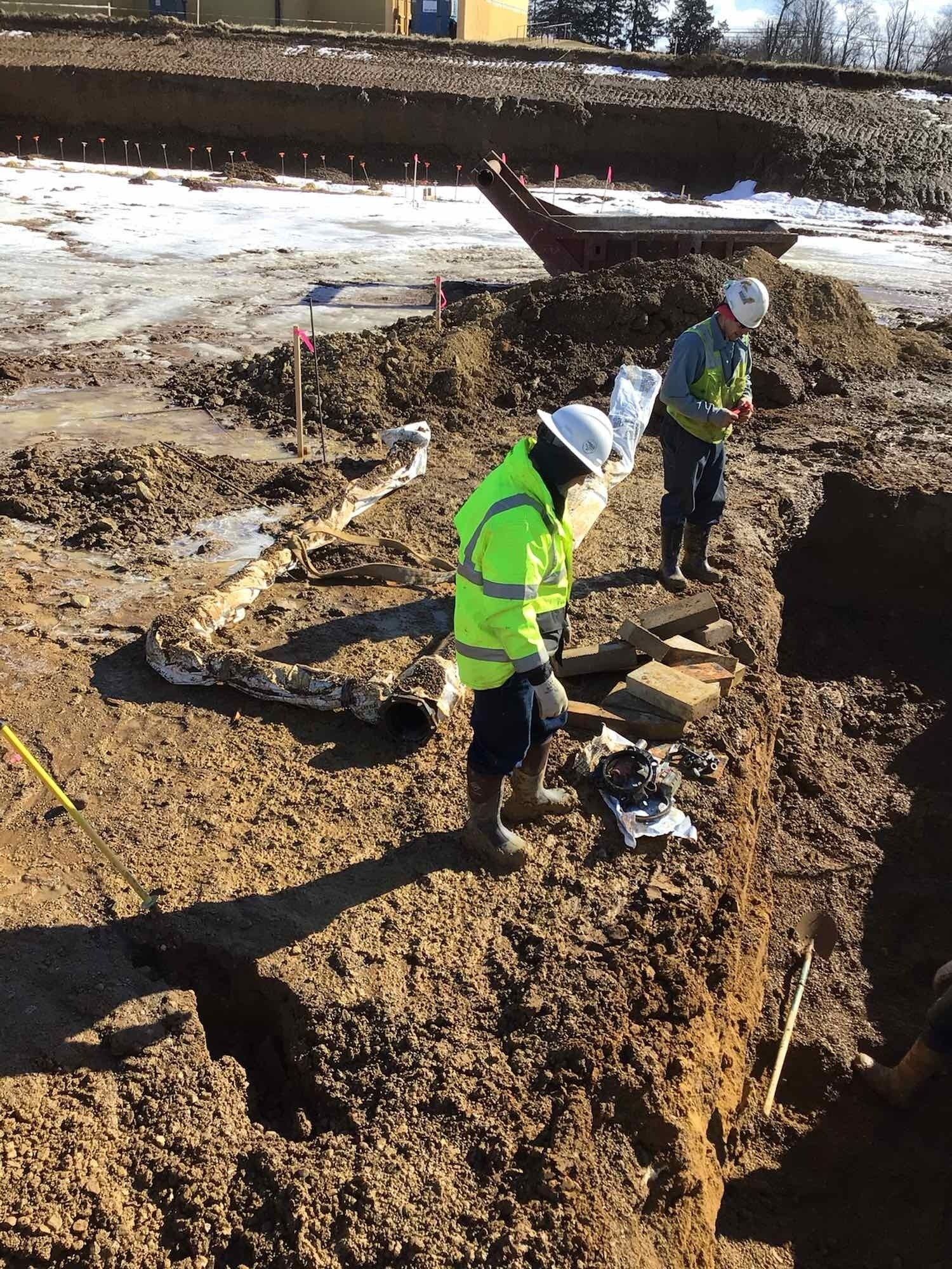 Two construction workers are digging in the dirt on a construction site.