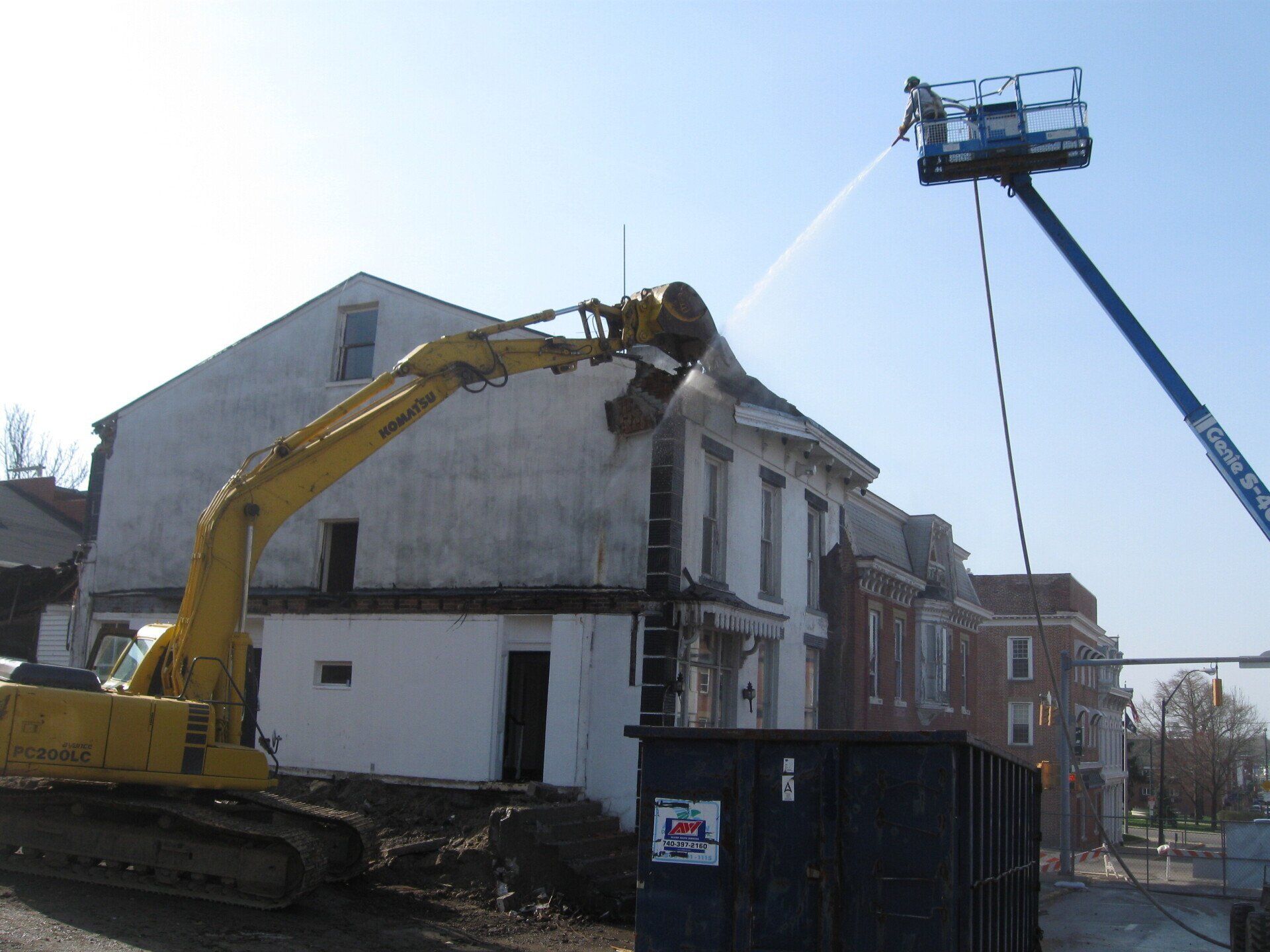 A yellow excavator is being used to demolish a building