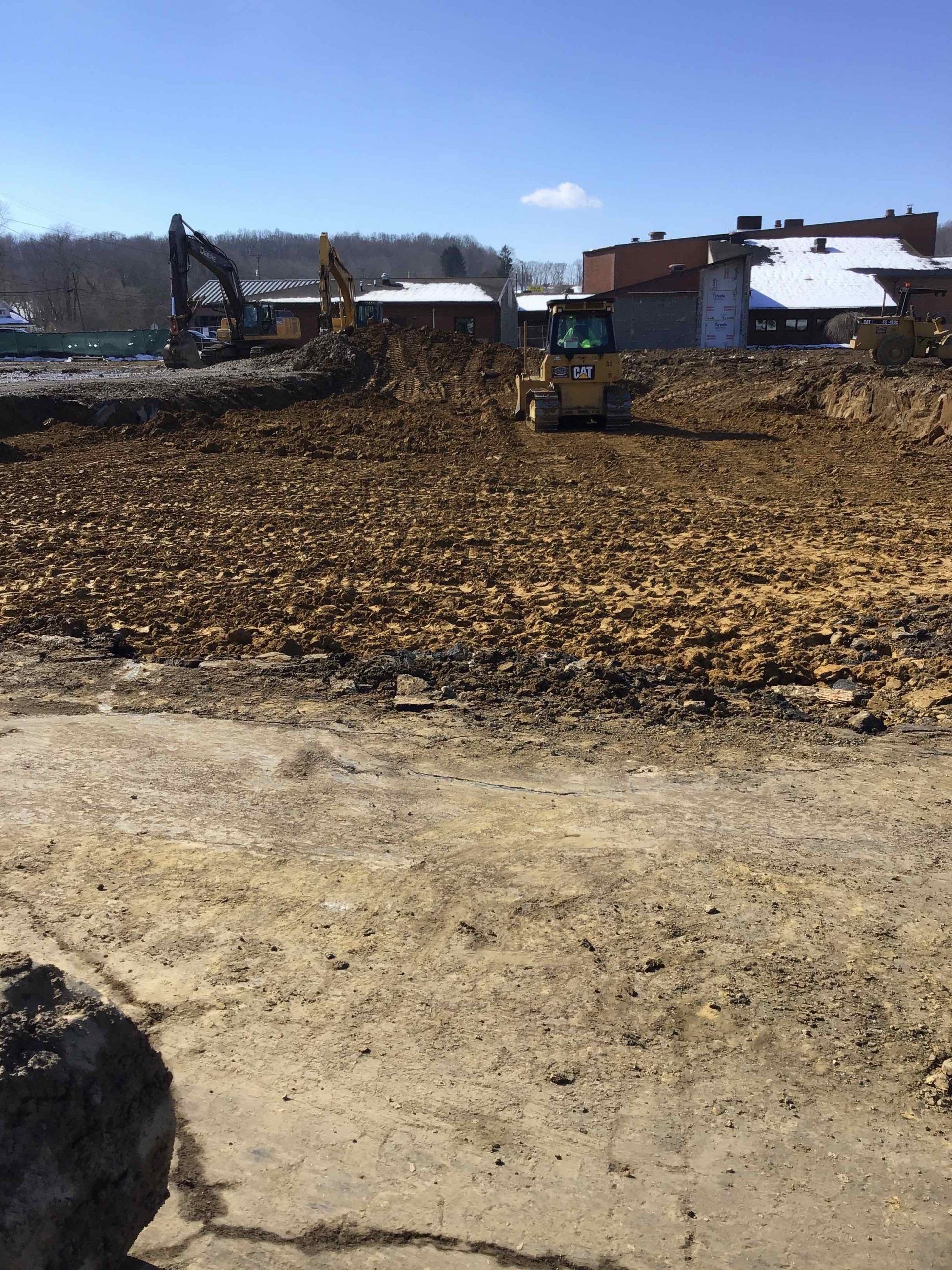 A large pile of dirt is being cleared by a bulldozer.