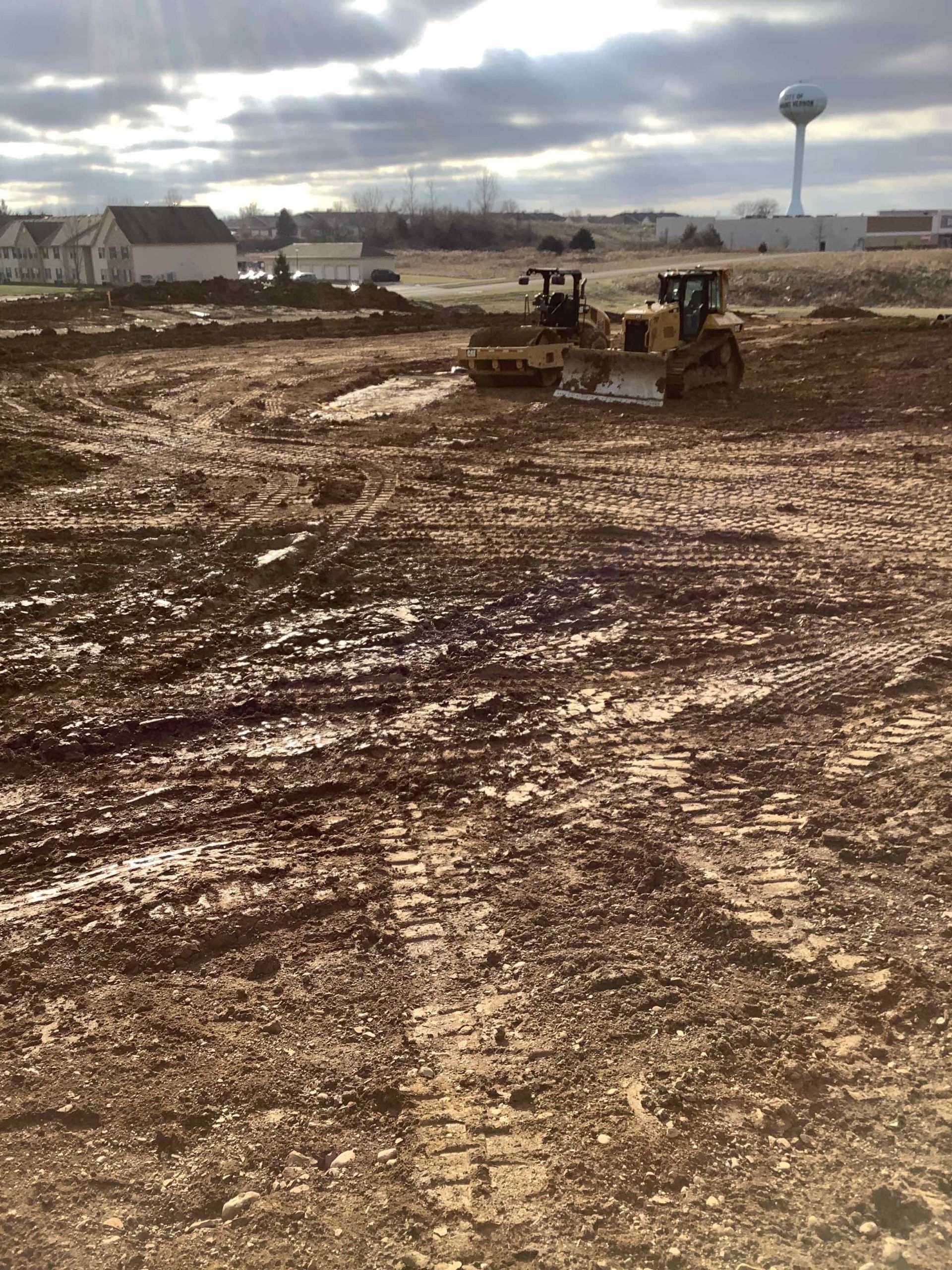 A bulldozer is moving dirt in a muddy field.