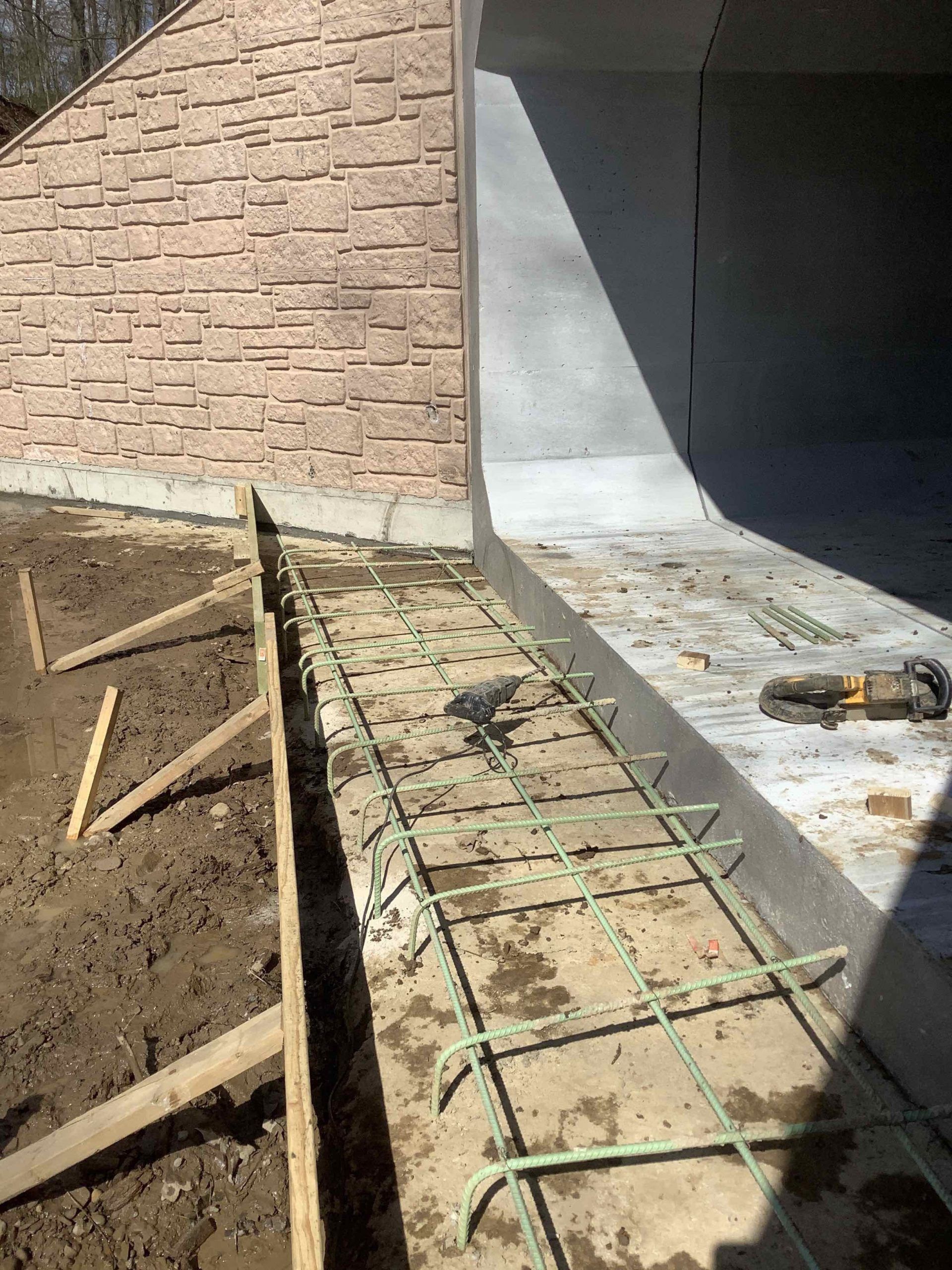 A concrete walkway is being built next to a brick wall.