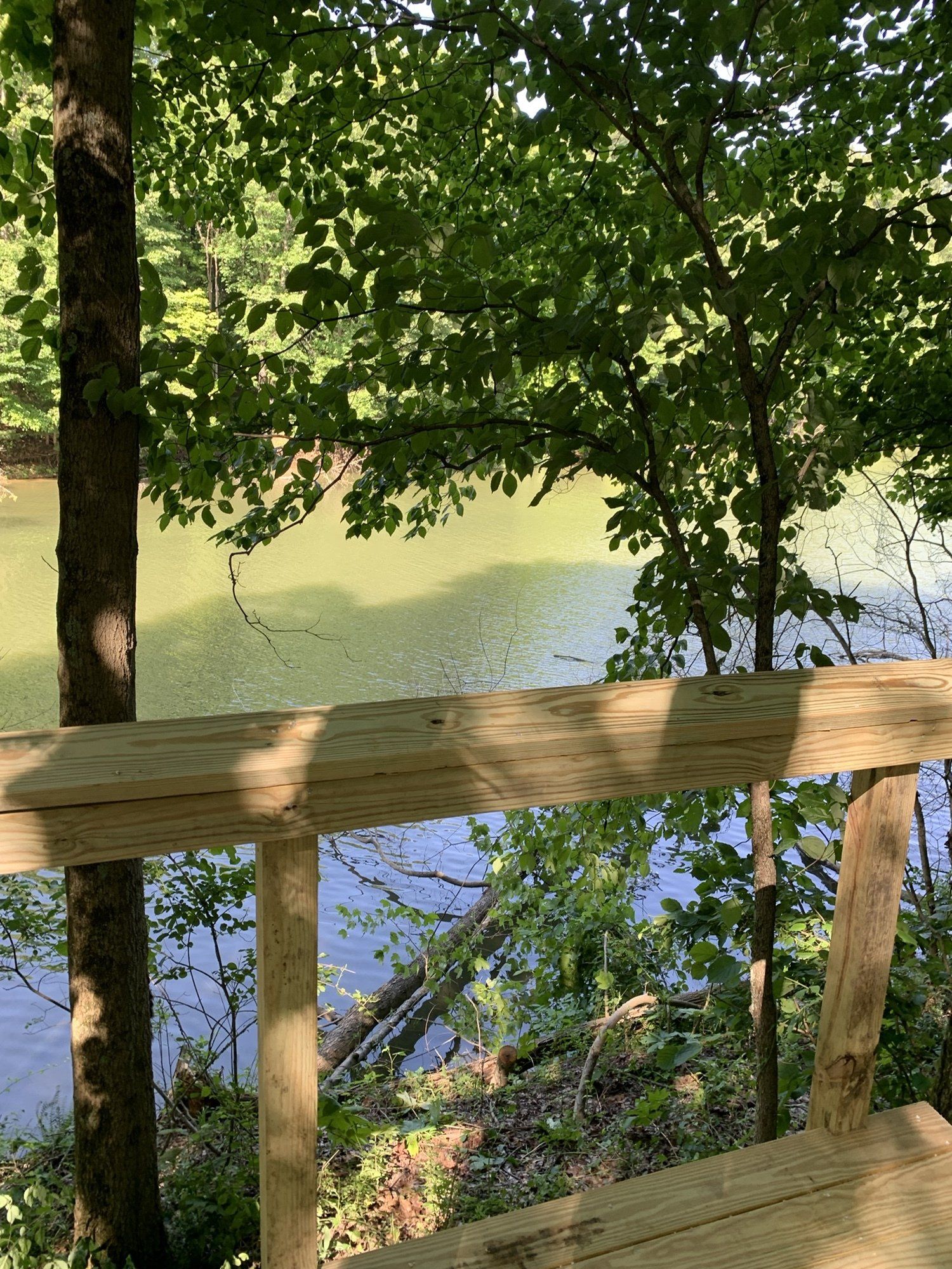 A wooden deck overlooking a lake in the woods.
