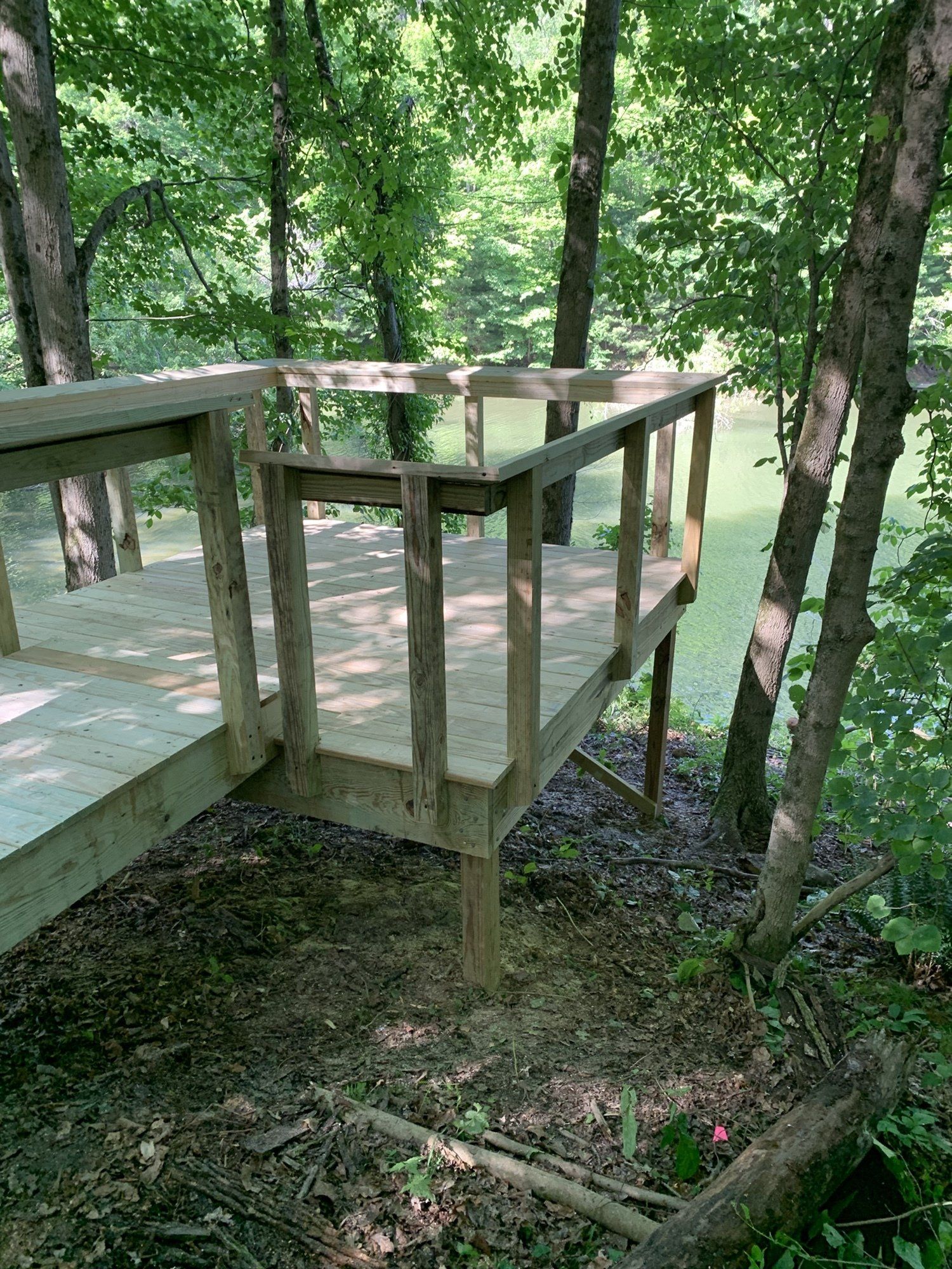 A wooden deck in the middle of a forest next to a body of water.