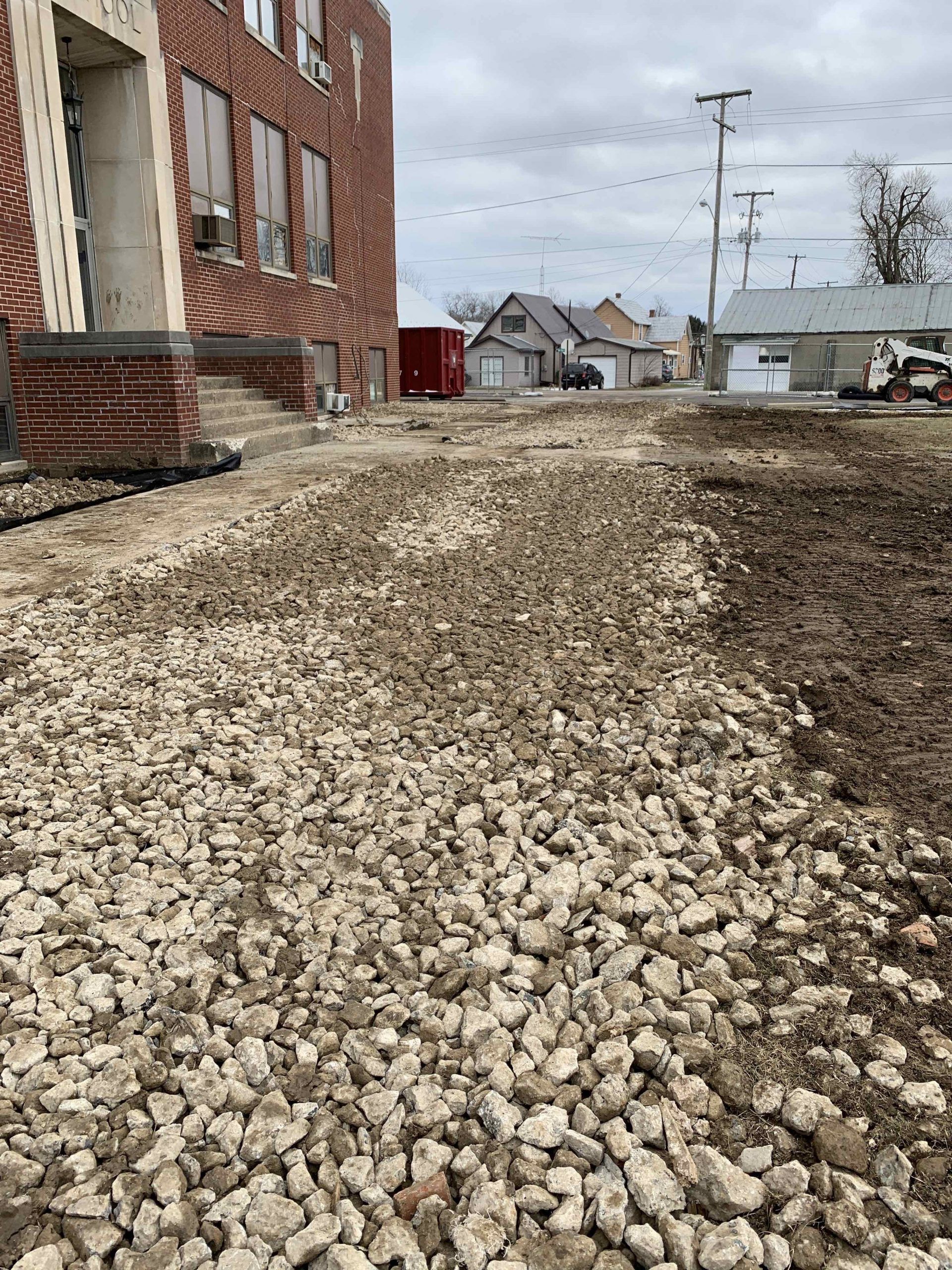 A pile of gravel is sitting in front of a brick building.