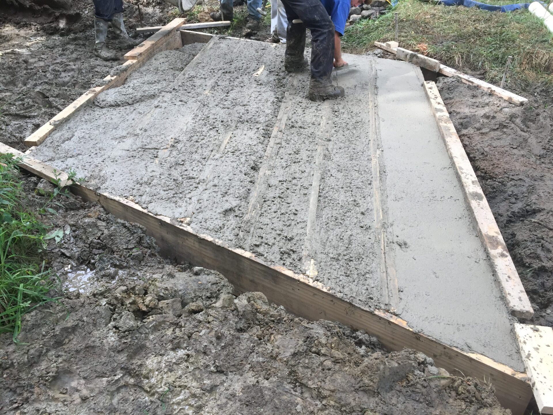 A group of people are working on a concrete walkway.