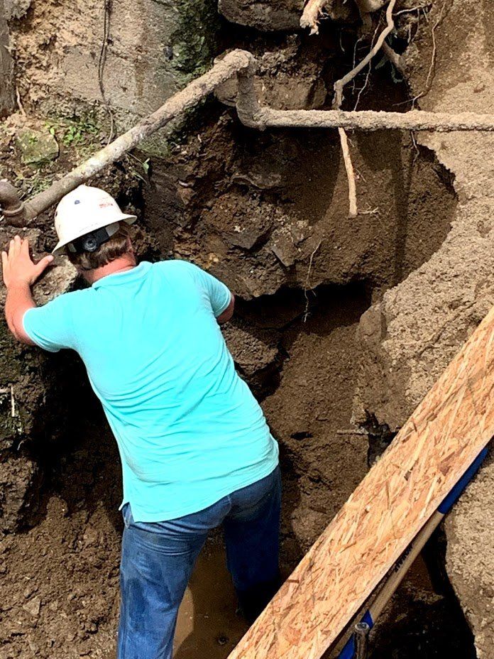 A man wearing a hard hat is digging in the dirt.