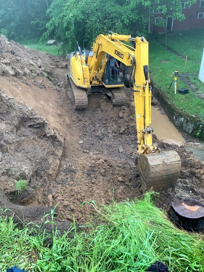 A yellow excavator is digging a hole in the dirt.