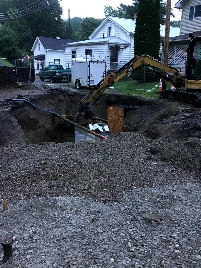 A large excavator is digging a hole in the ground in front of a house.