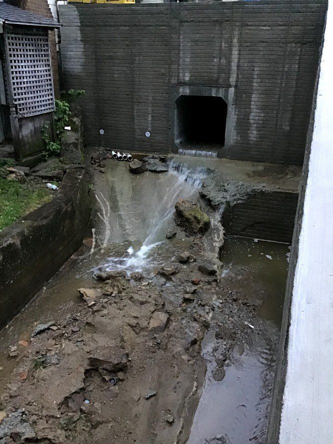 A stream of water is coming out of a hole in a brick wall.