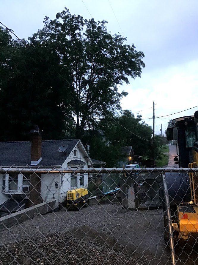A yellow bulldozer is parked in front of a chain link fence.