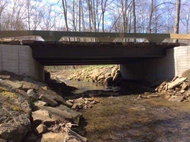 A bridge over a river with rocks and trees in the background.