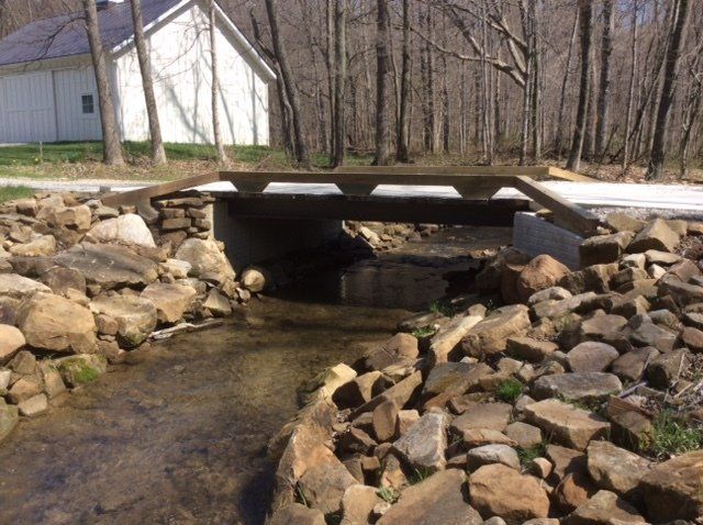 A wooden bridge over a stream surrounded by rocks and trees.