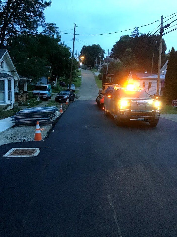 A truck with a yellow light on the back is driving down a street