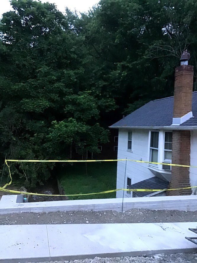 A white house with a brick chimney is surrounded by yellow tape