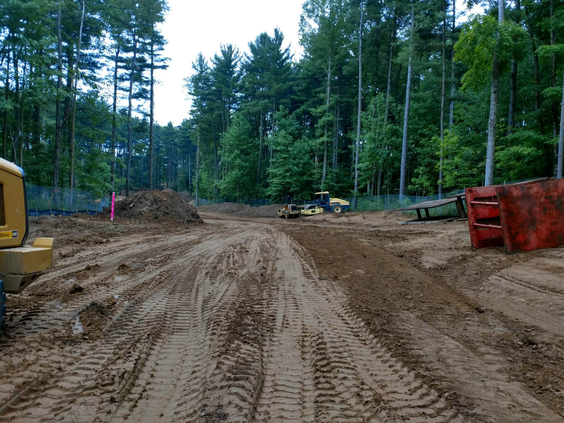 A muddy dirt road with trees in the background