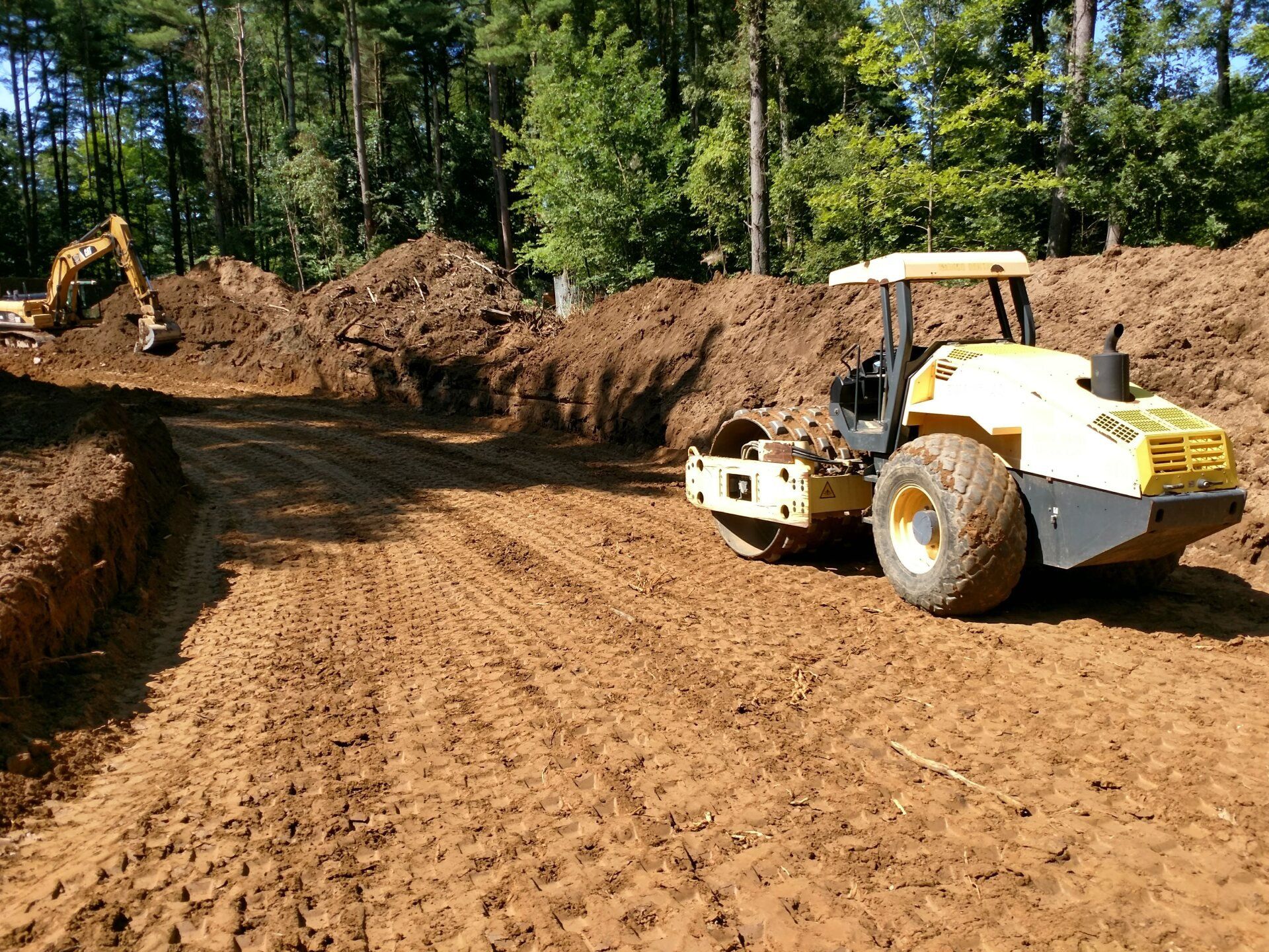 A yellow roller is sitting on top of a pile of dirt.