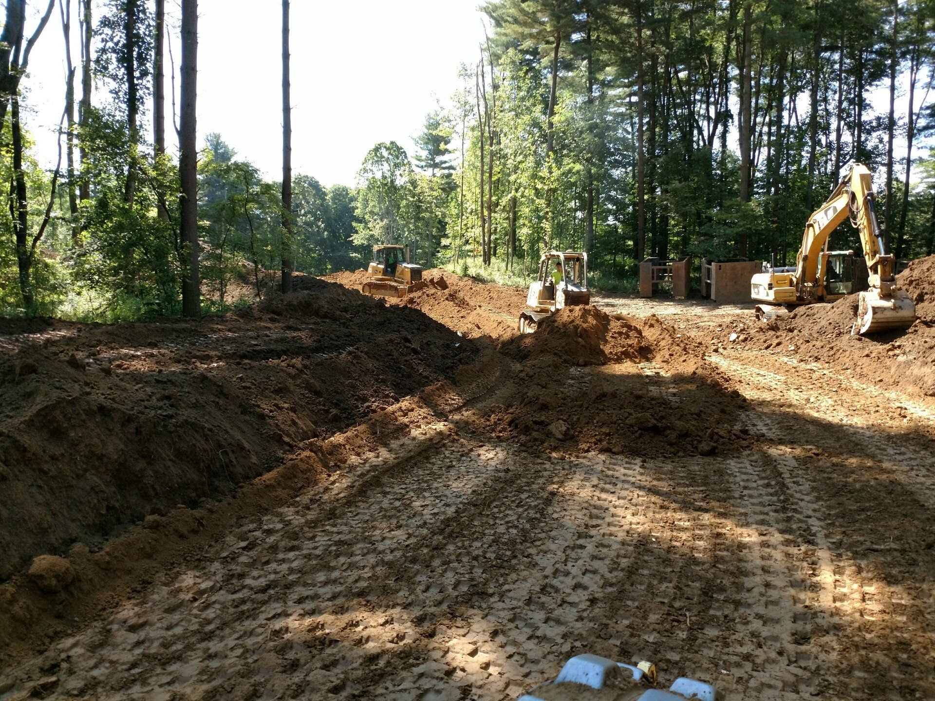 A construction site with a lot of dirt and trees in the background.
