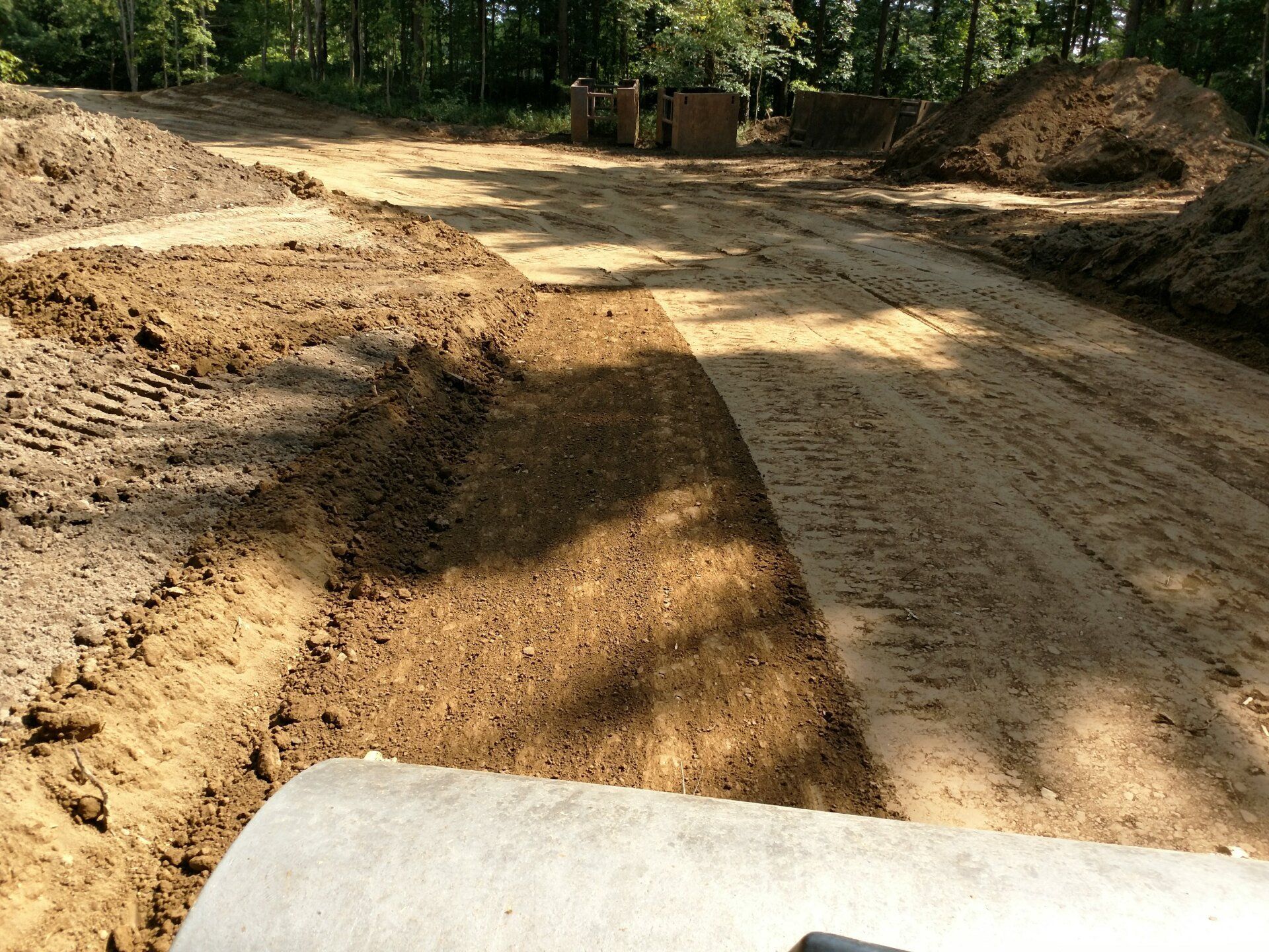 A construction site with a lot of dirt and trees in the background.