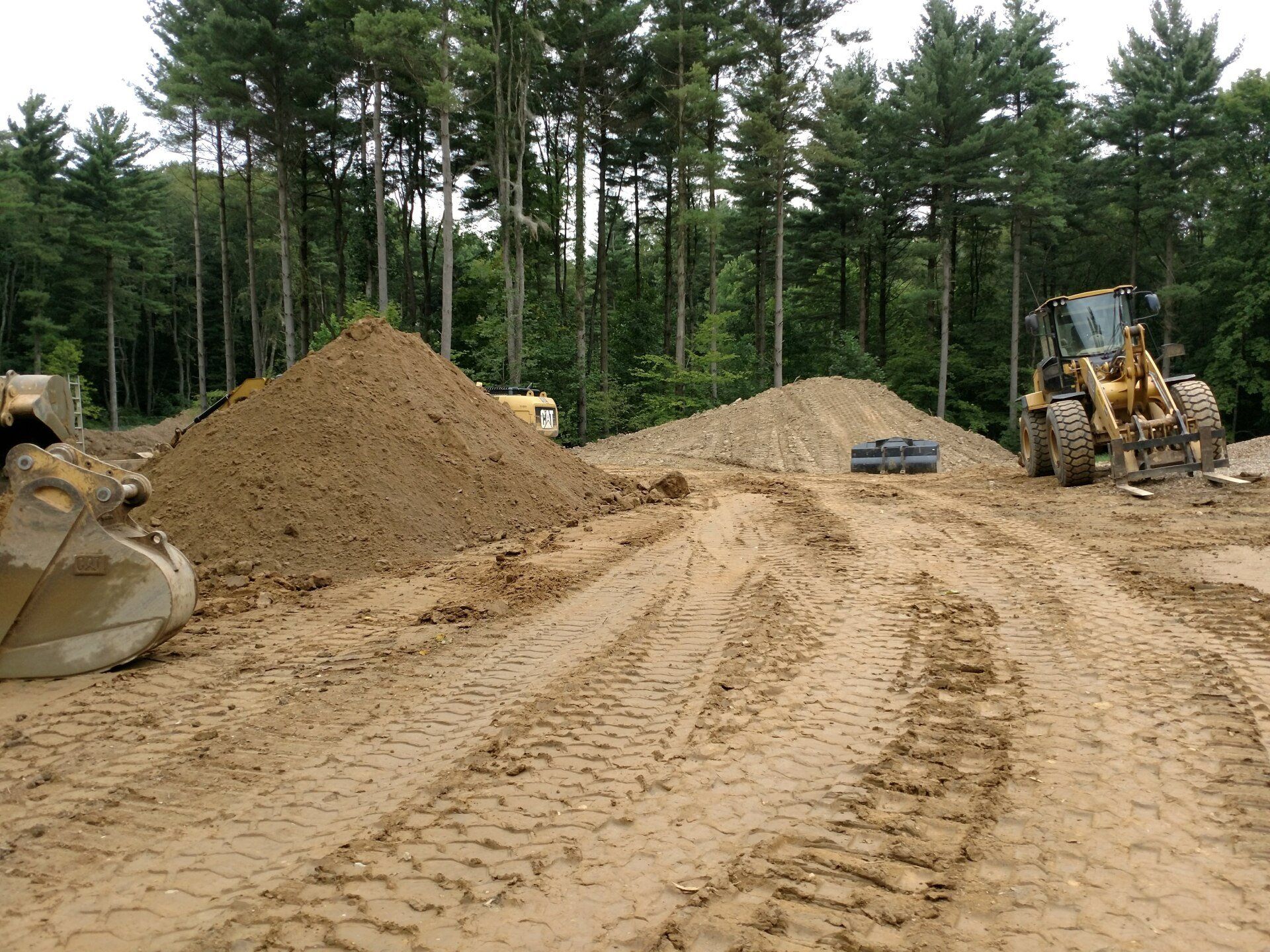 A construction site with a lot of dirt and trees in the background