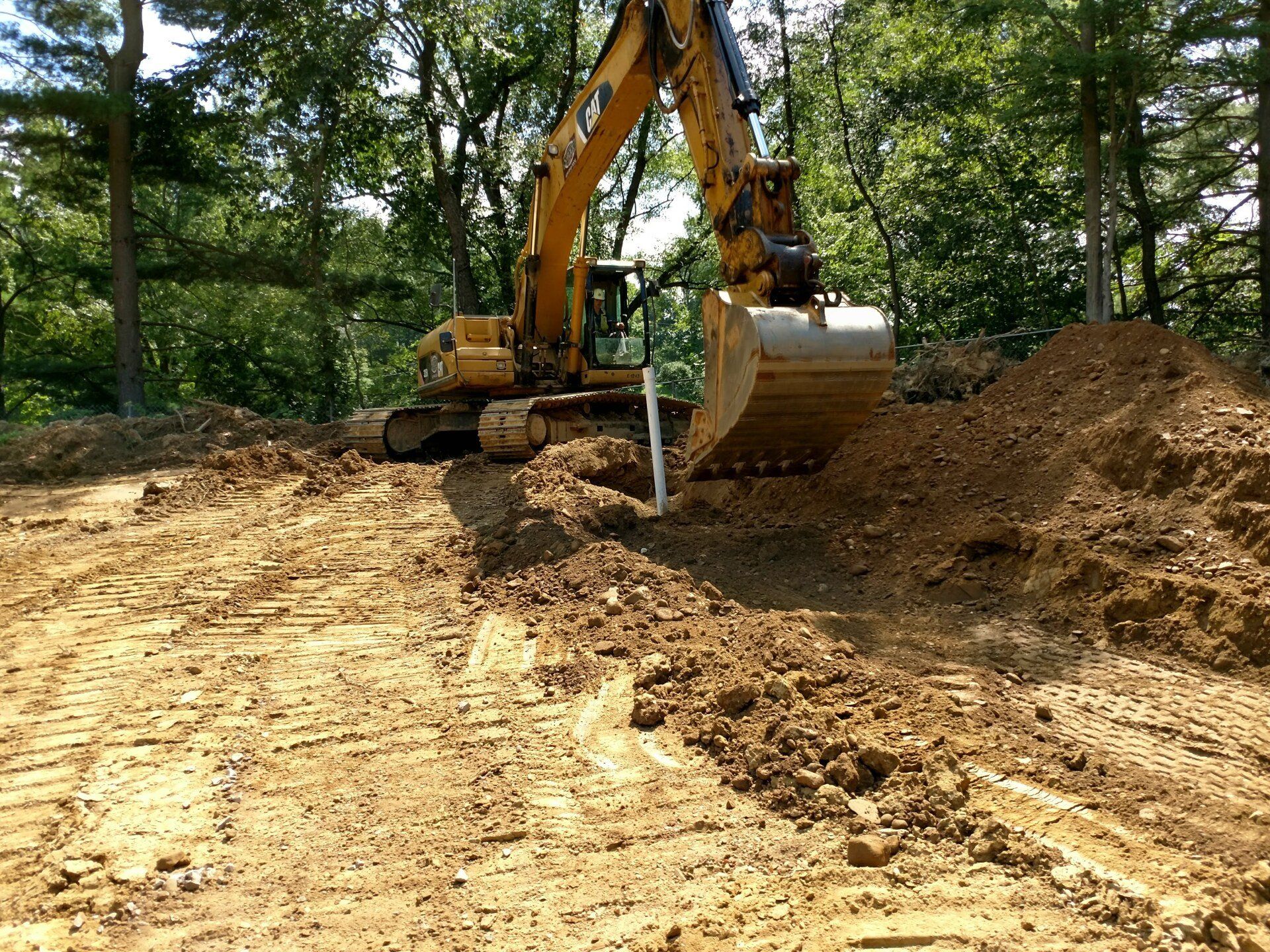 A large yellow excavator is digging a hole in the dirt.