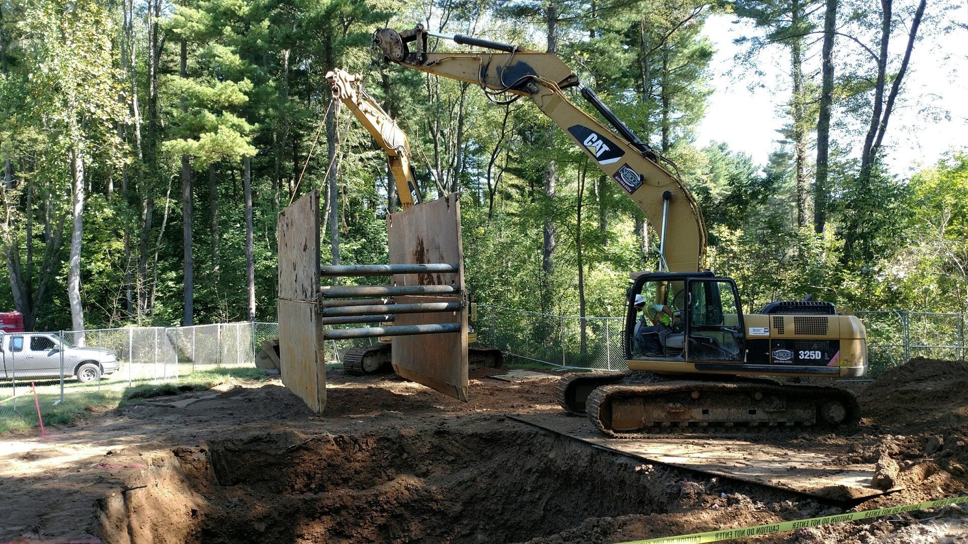 A large excavator is working on a construction site in the woods.