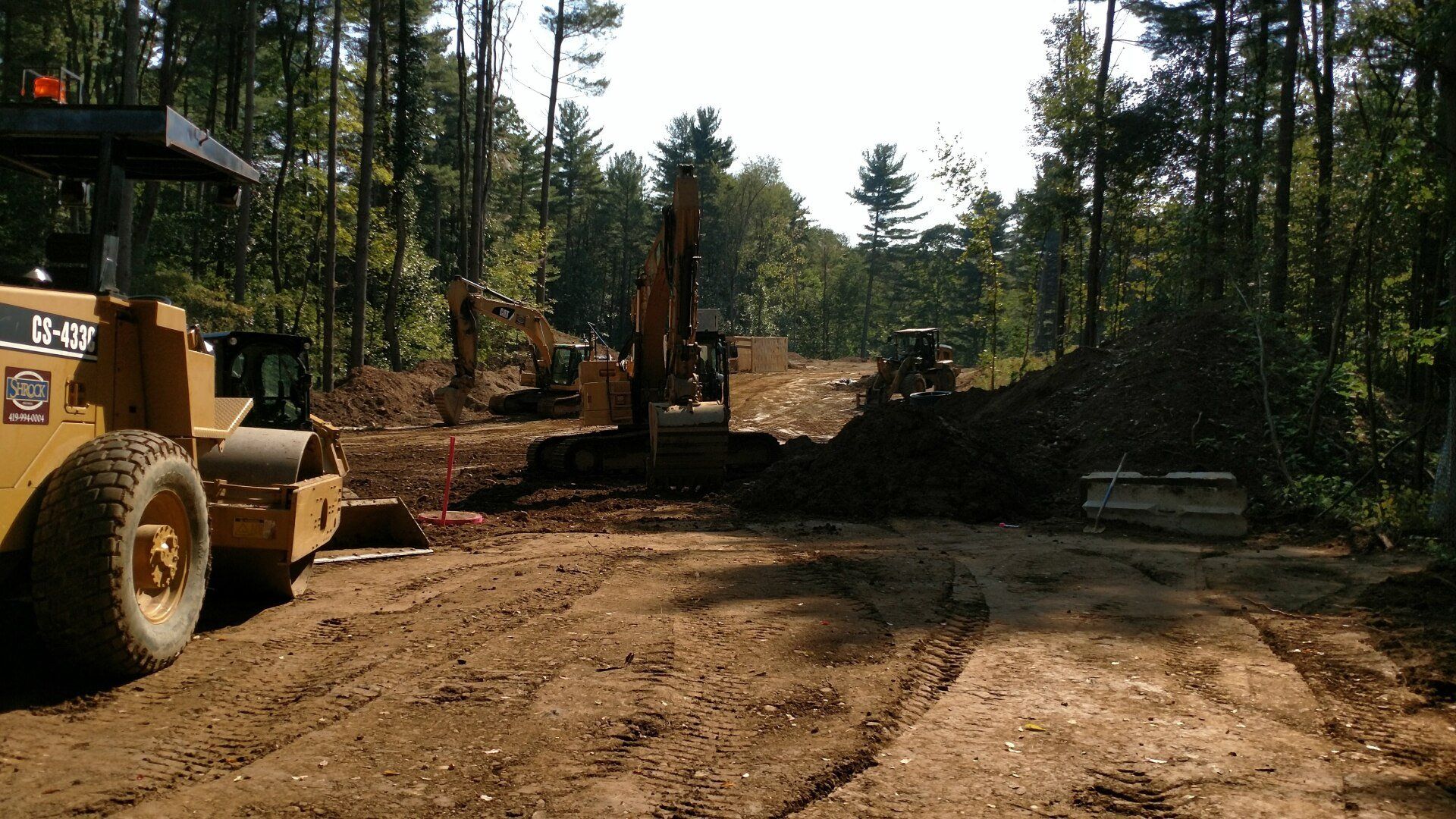 A cat tractor is driving down a dirt road