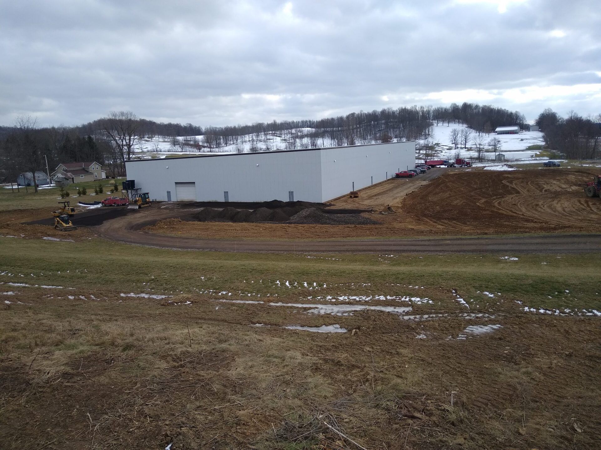 A large white building is in the middle of a field