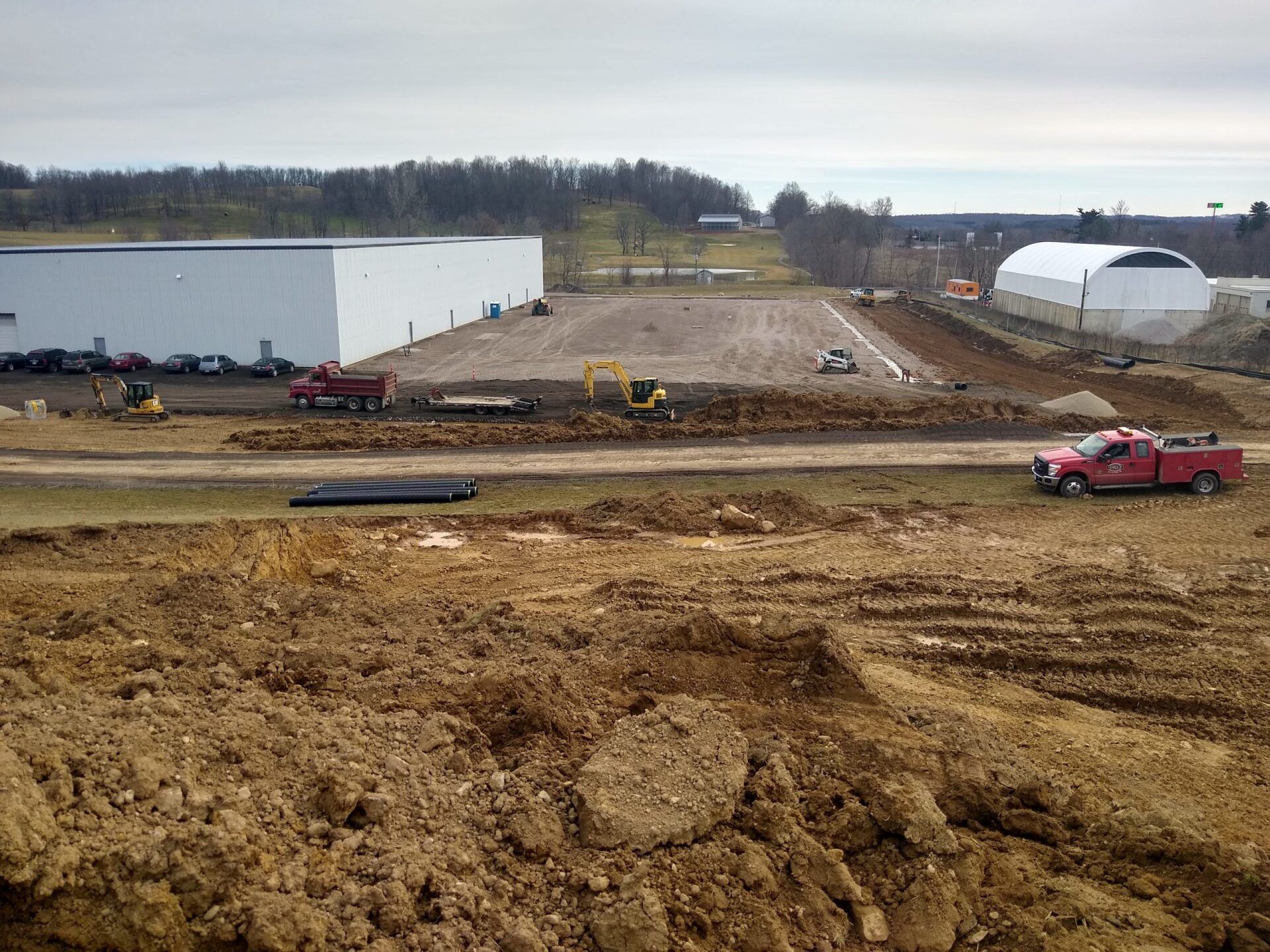 A red truck is parked in the middle of a dirt field.