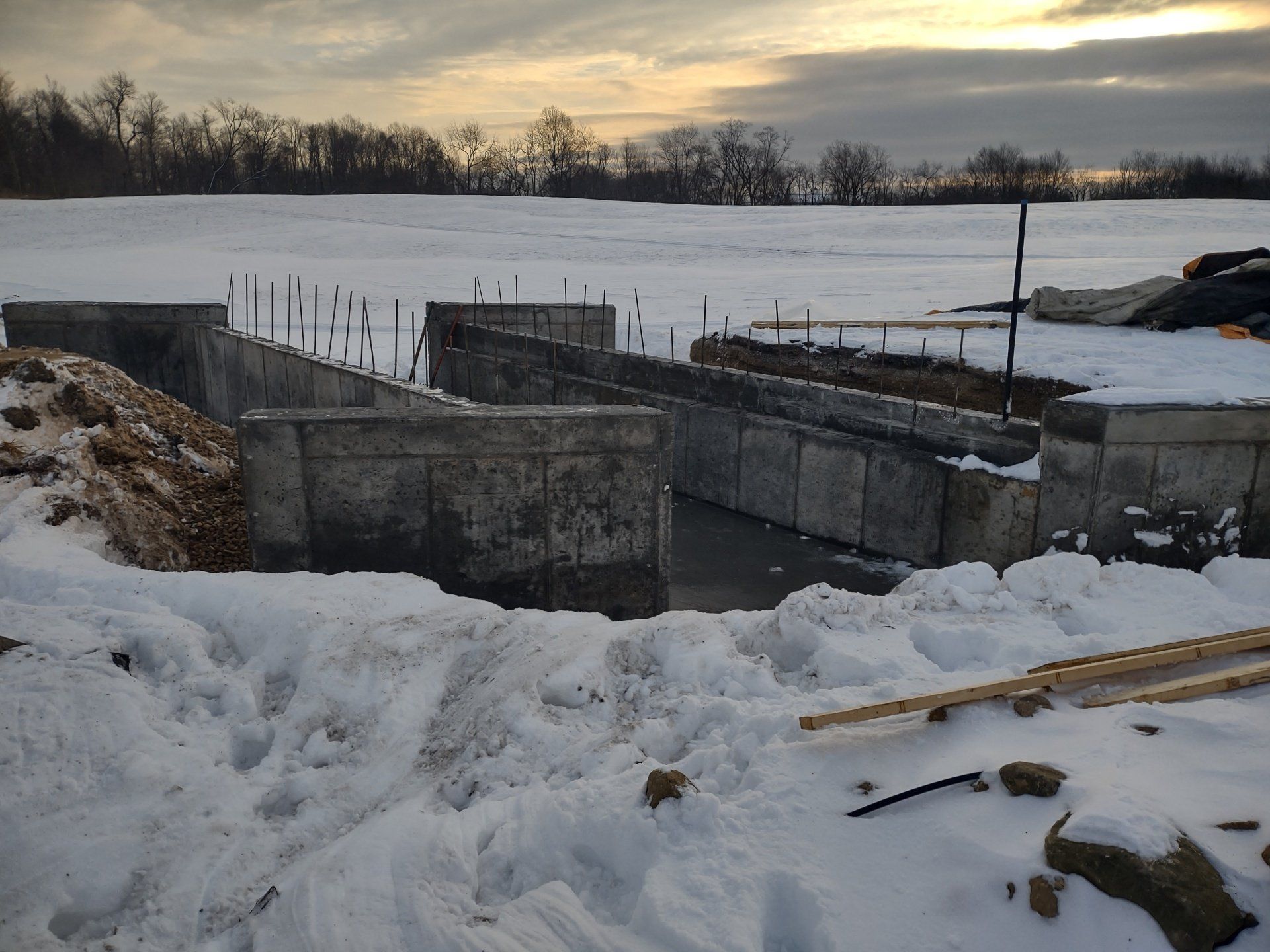 A snowy field with a concrete wall in the foreground