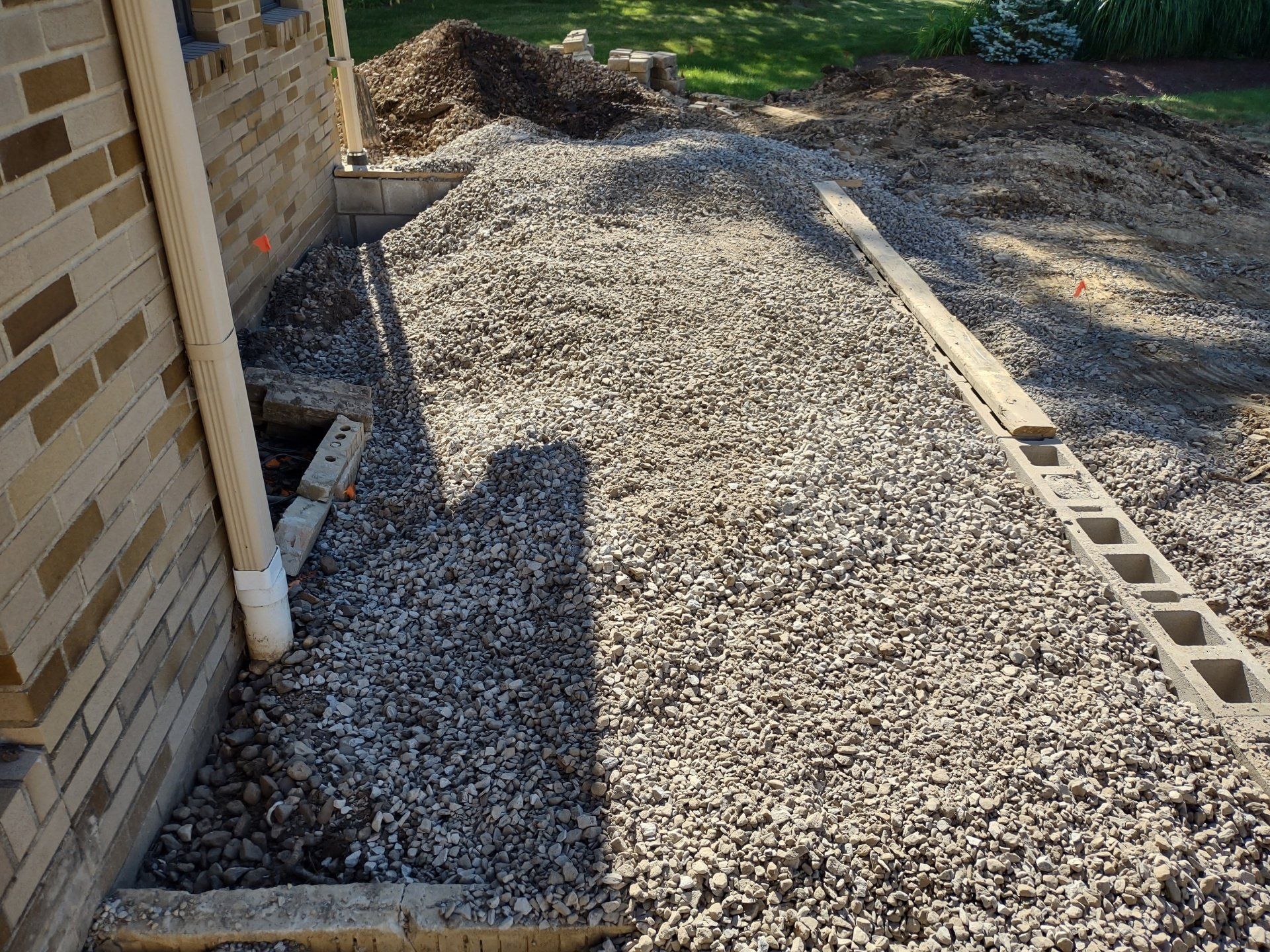 A pile of gravel is sitting next to a brick wall.