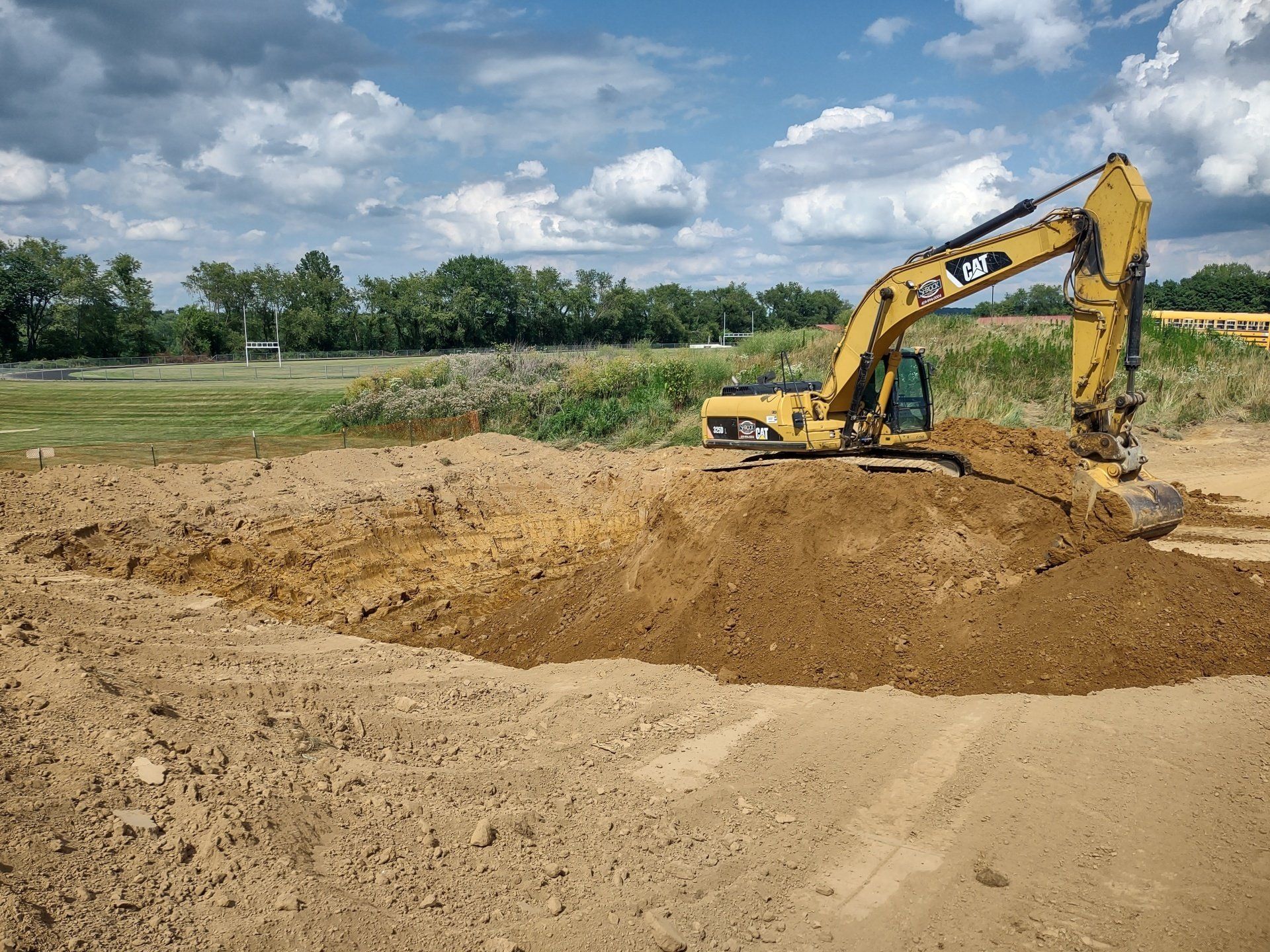 A large yellow excavator is digging a hole in the dirt.